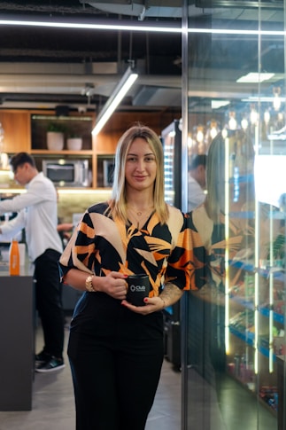 Woman holding a mug in a modern office kitchen.