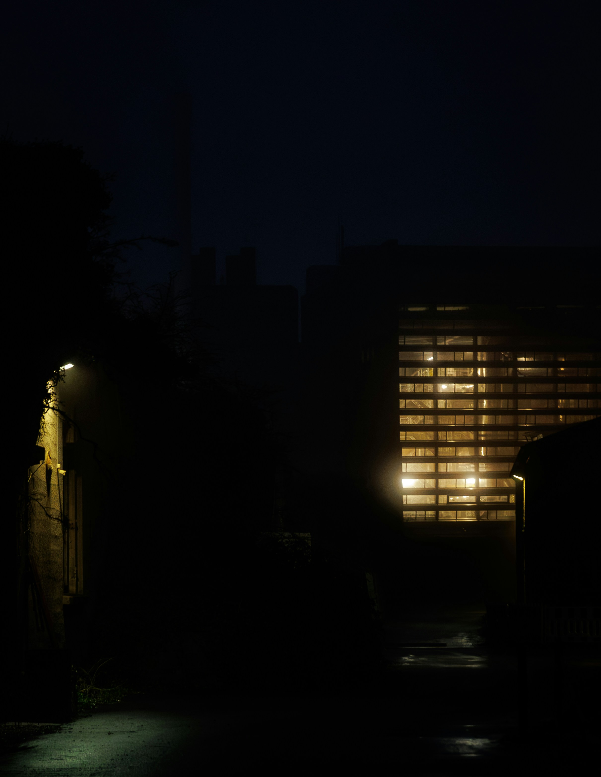 Dark alleyway with glowing window at night
