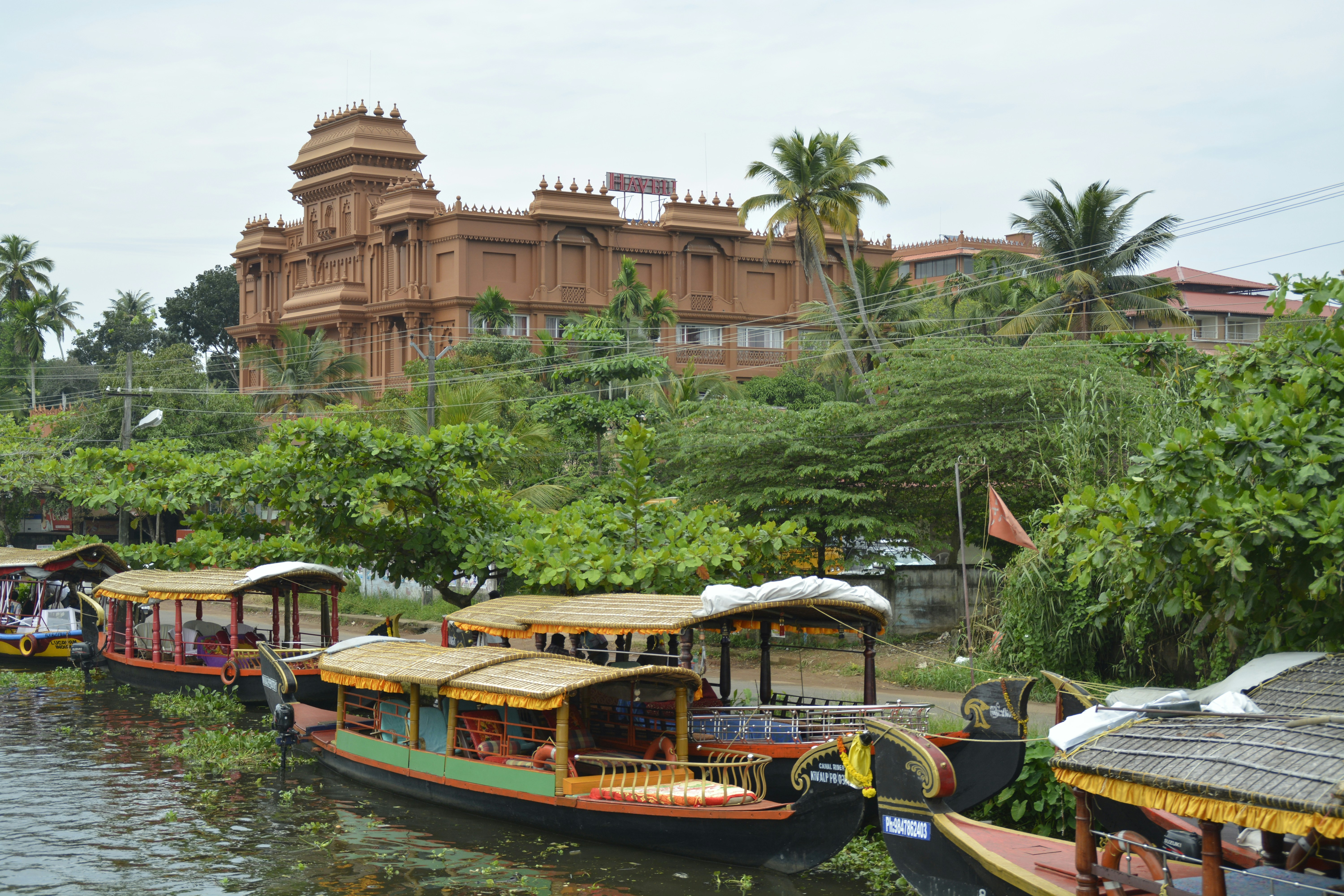 Boats docked on a river with a large building behind.