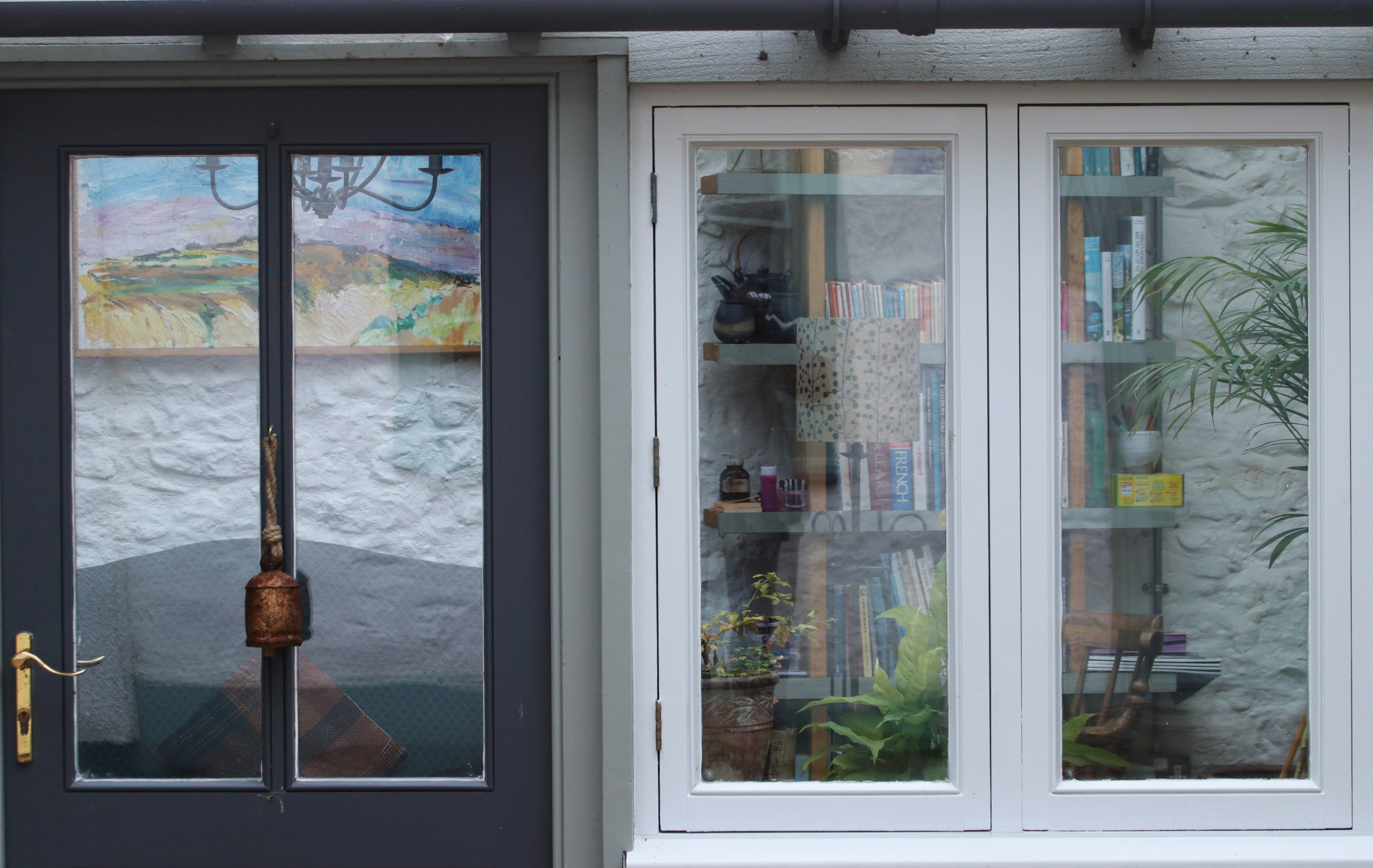 A dark door and a white window with books visible.