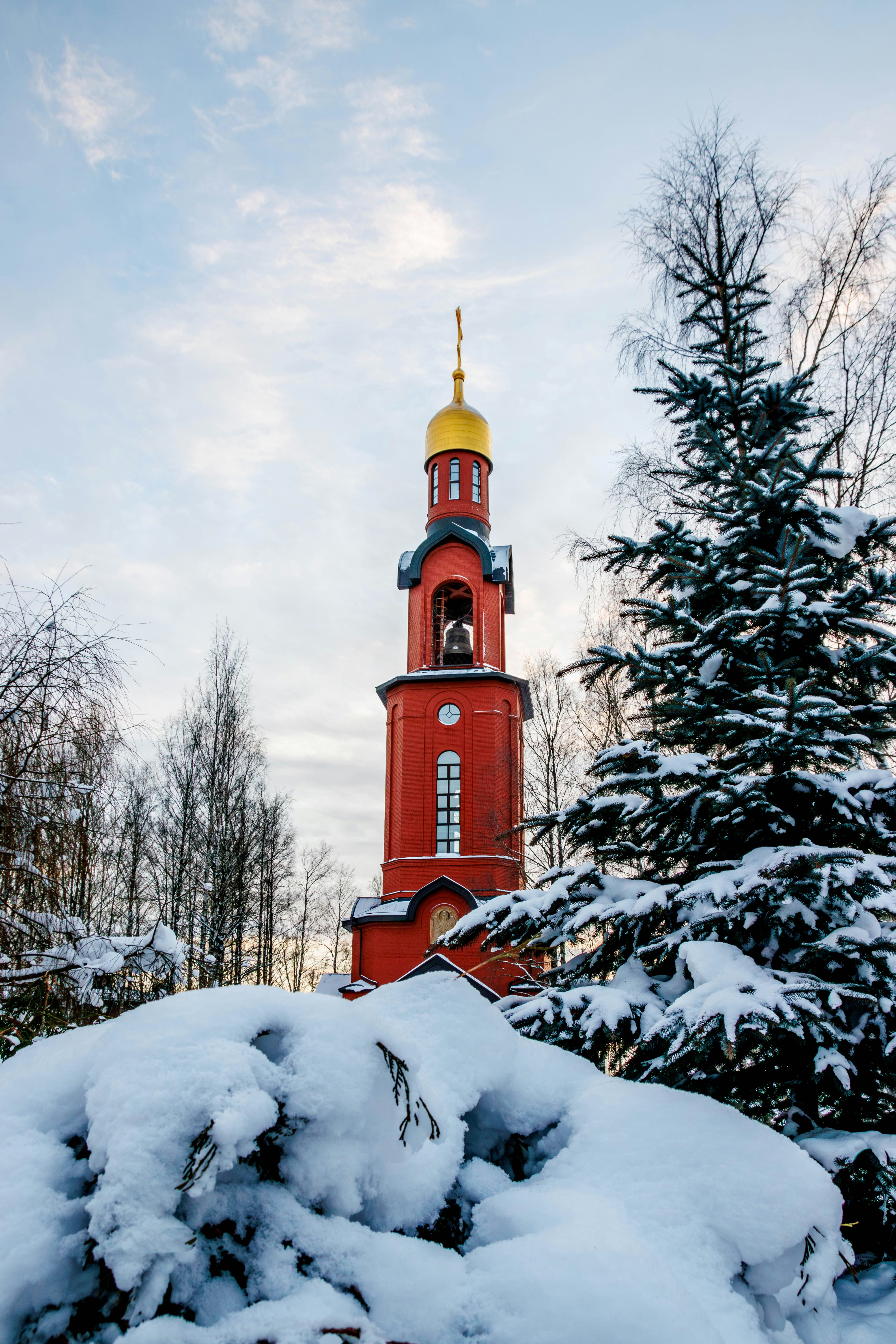 Red church tower with golden dome in winter snow