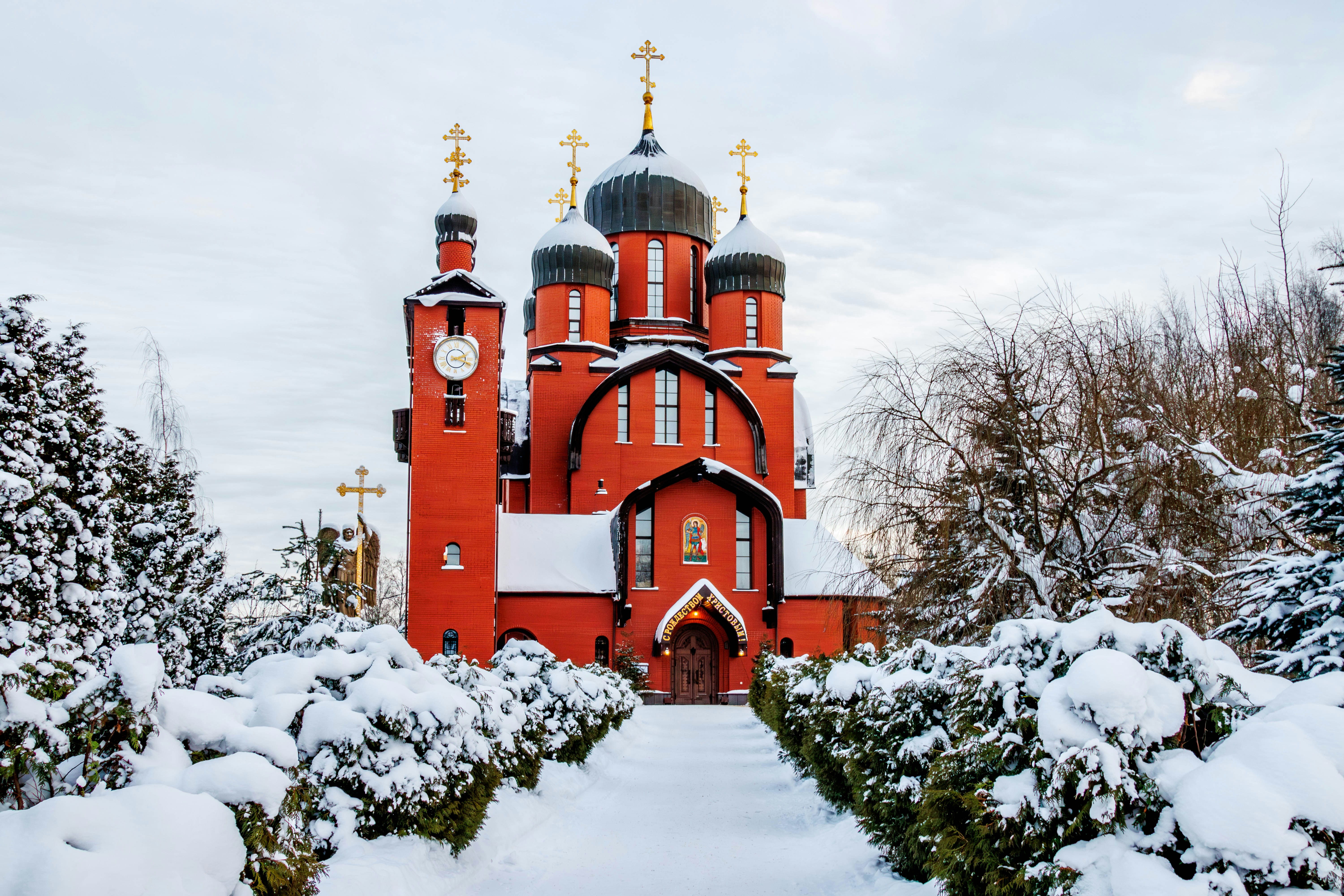 Red church with black domes in snowy landscape
