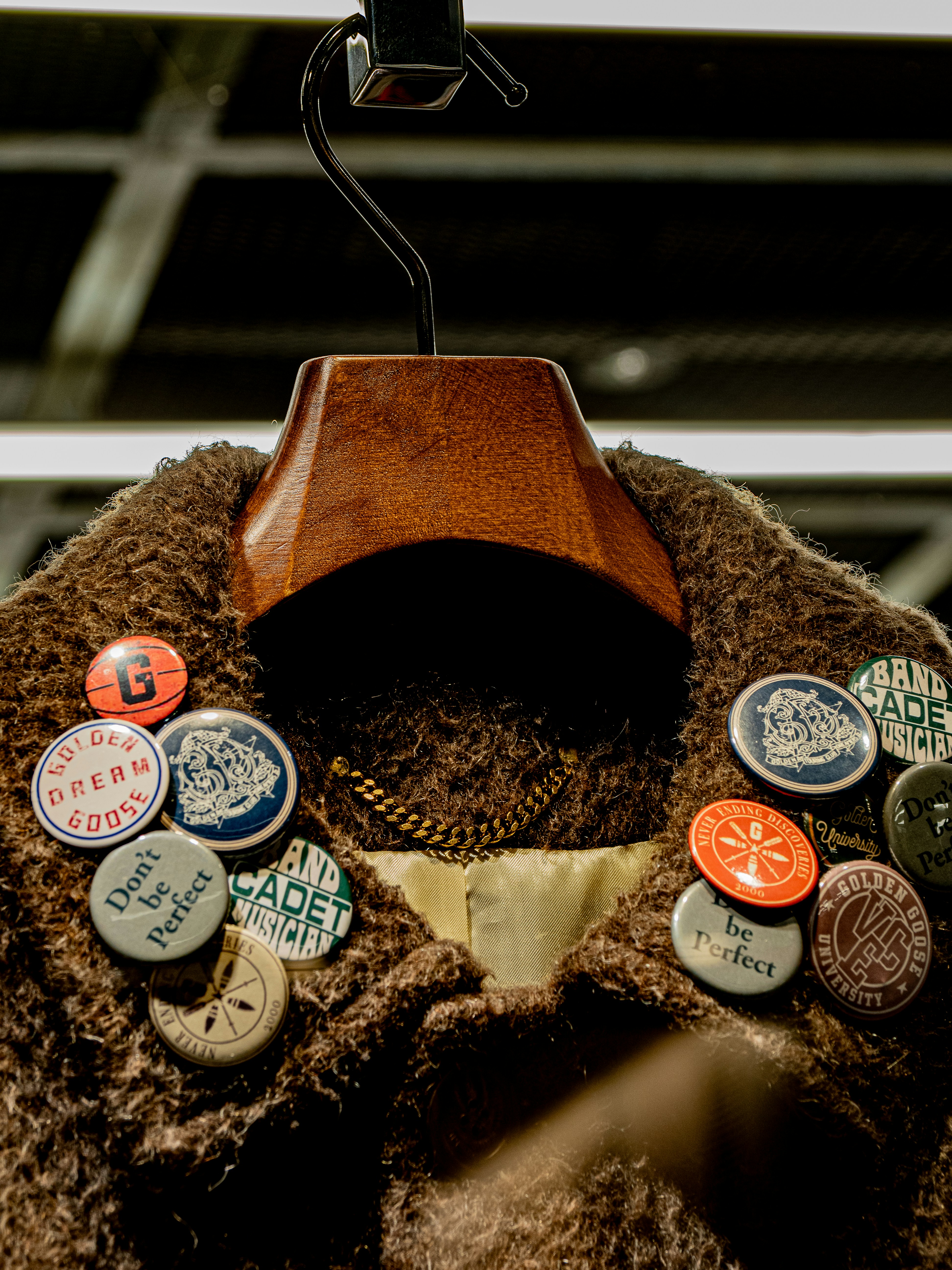 Braune, pelzige Jacke mit vielen Nadeln und Kette