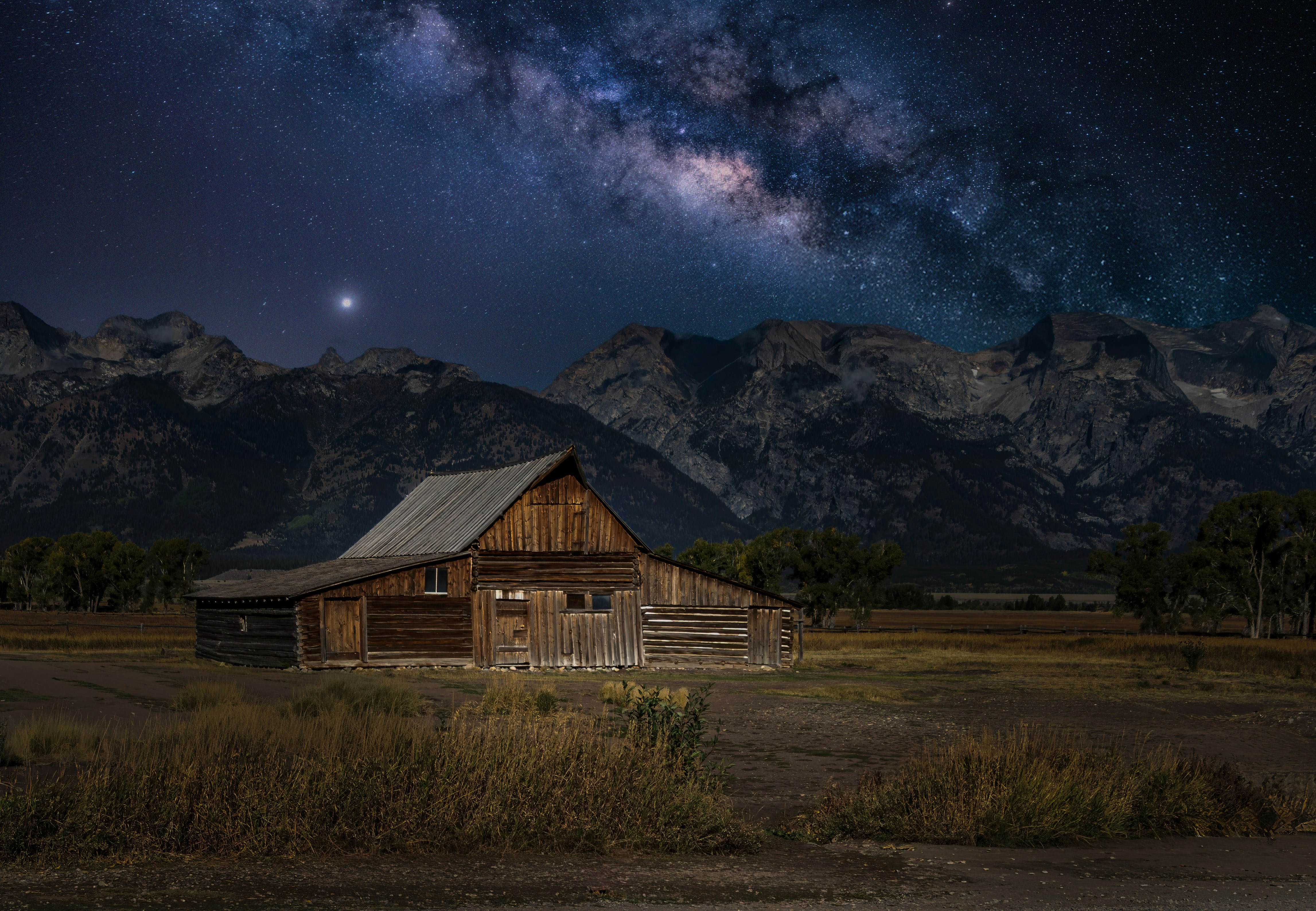 Fienile rustico sotto un cielo stellato con montagne.