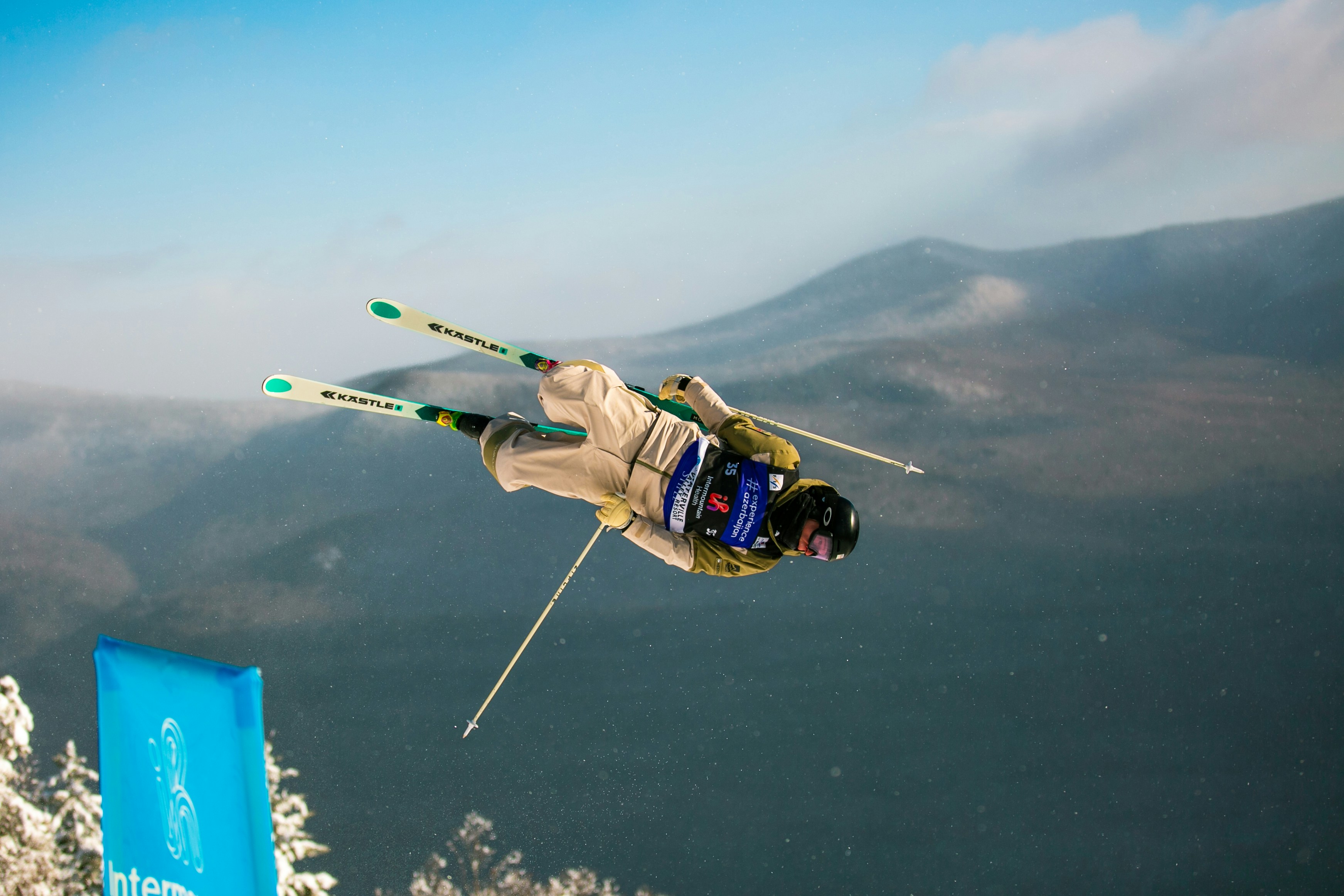 Skier performing a flip mid-air against snowy mountains
