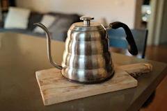 A stainless steel gooseneck kettle on a wooden board