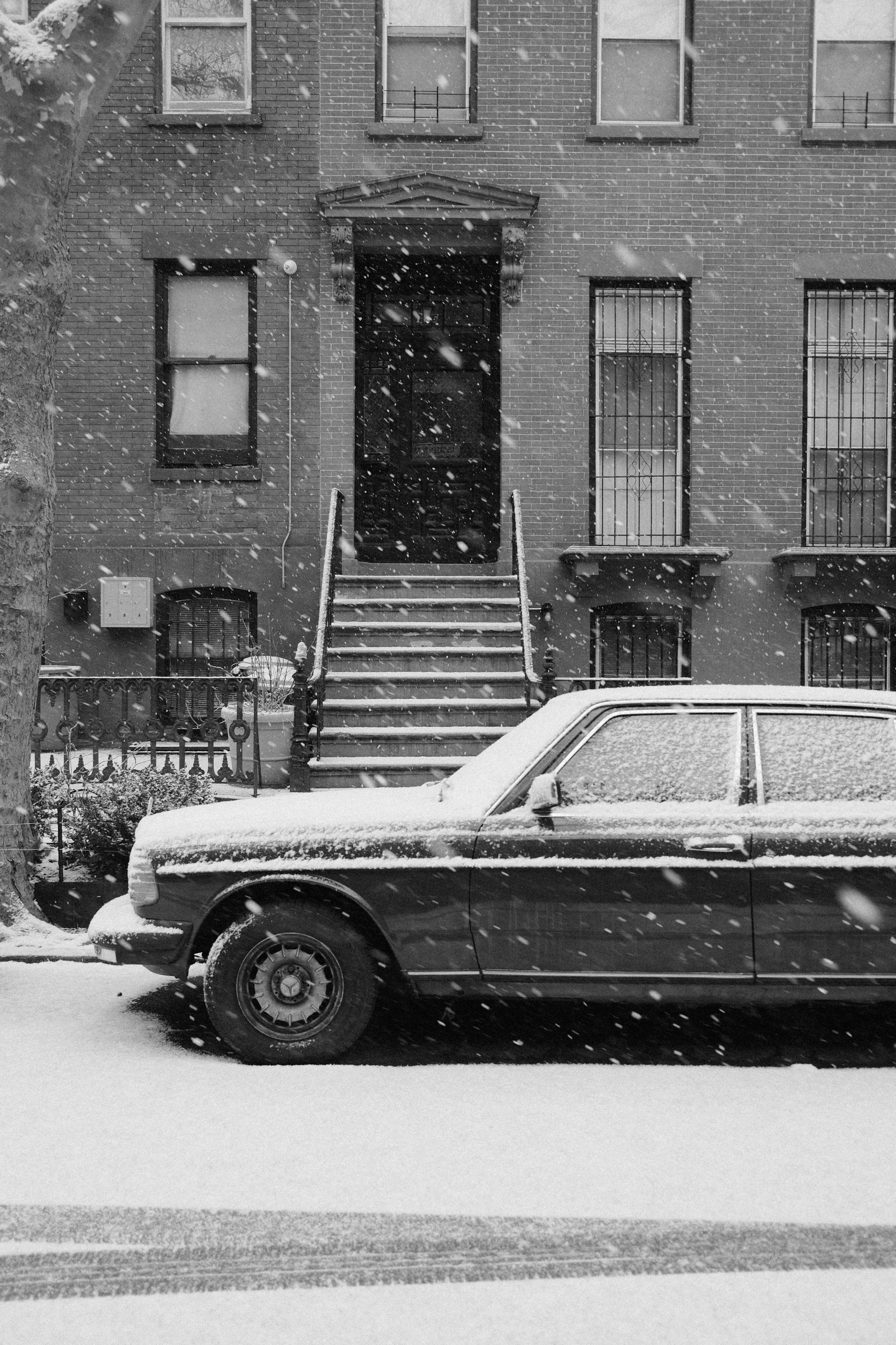 Car parked outside brownstone during snowfall
