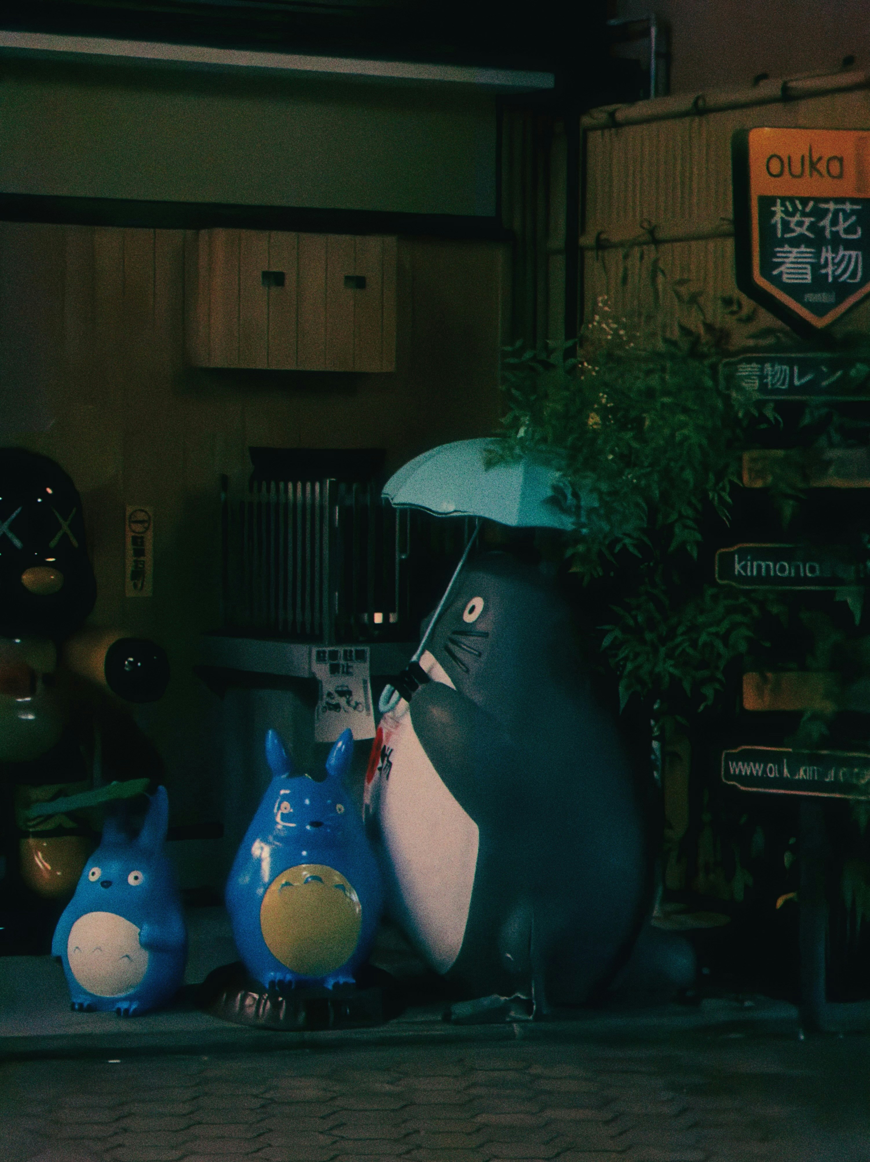 Three totoro statues with umbrellas at night