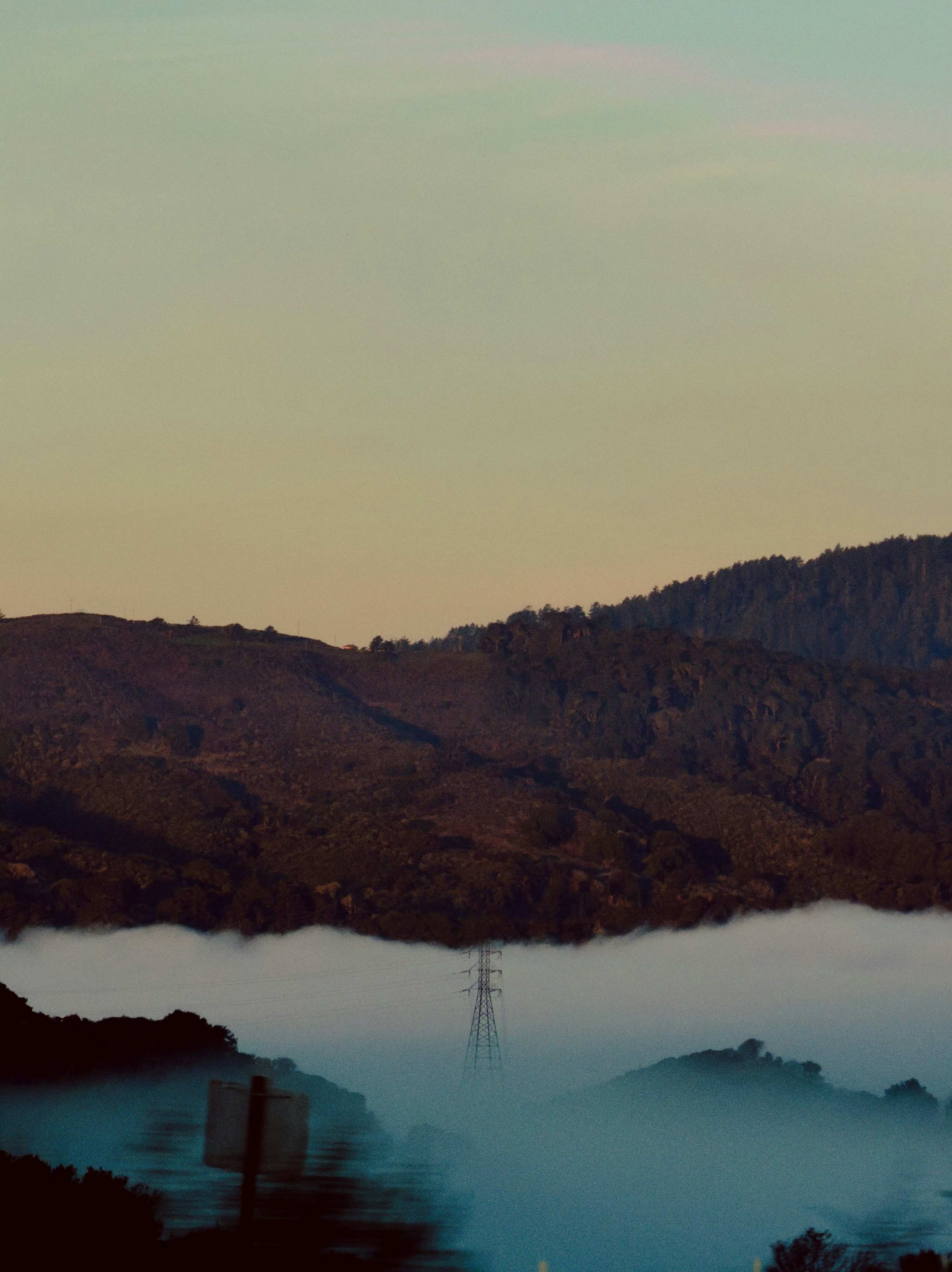 Misty mountains with a power line tower at sunrise
