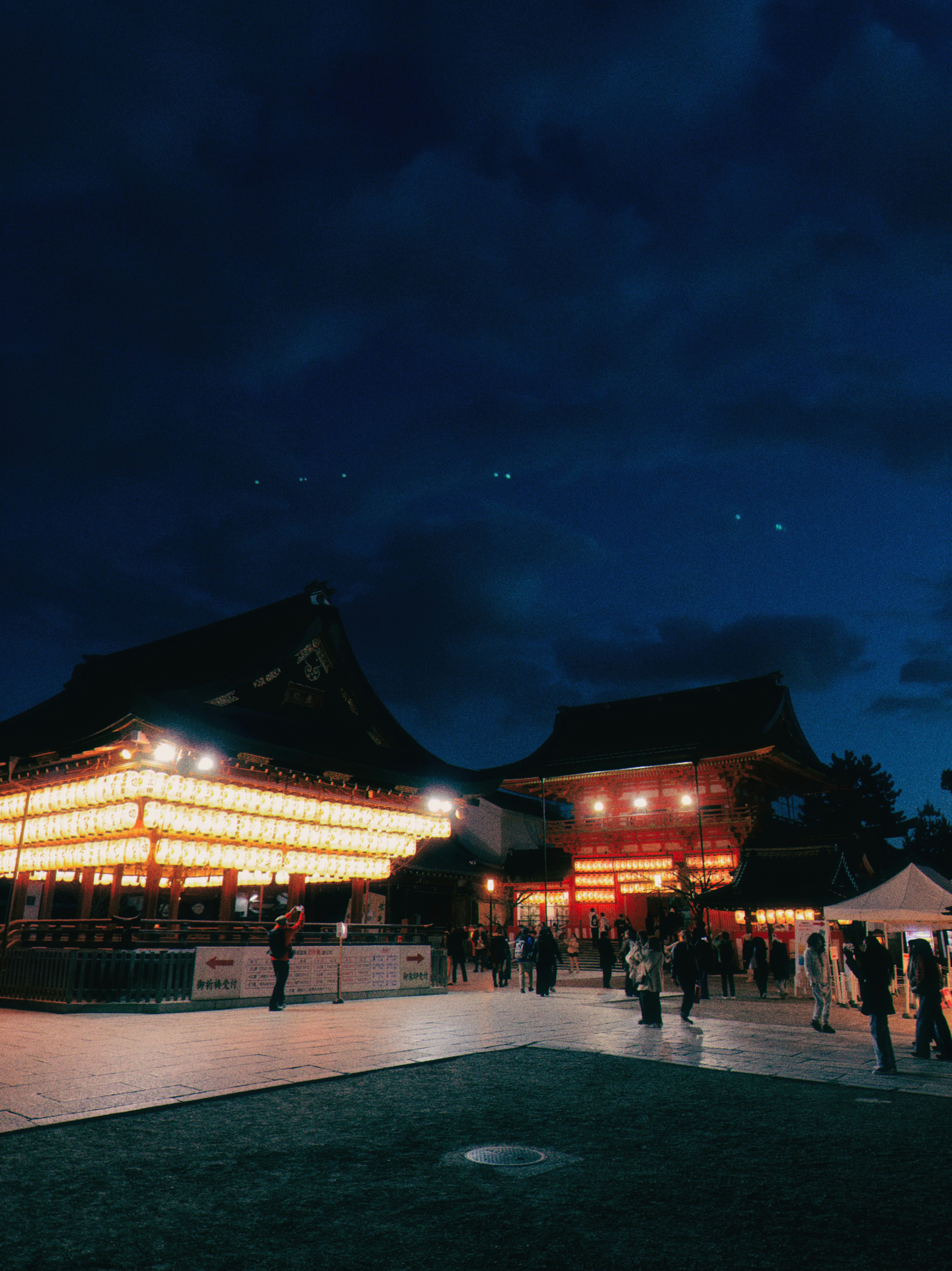 Illuminated temple buildings at dusk with people walking