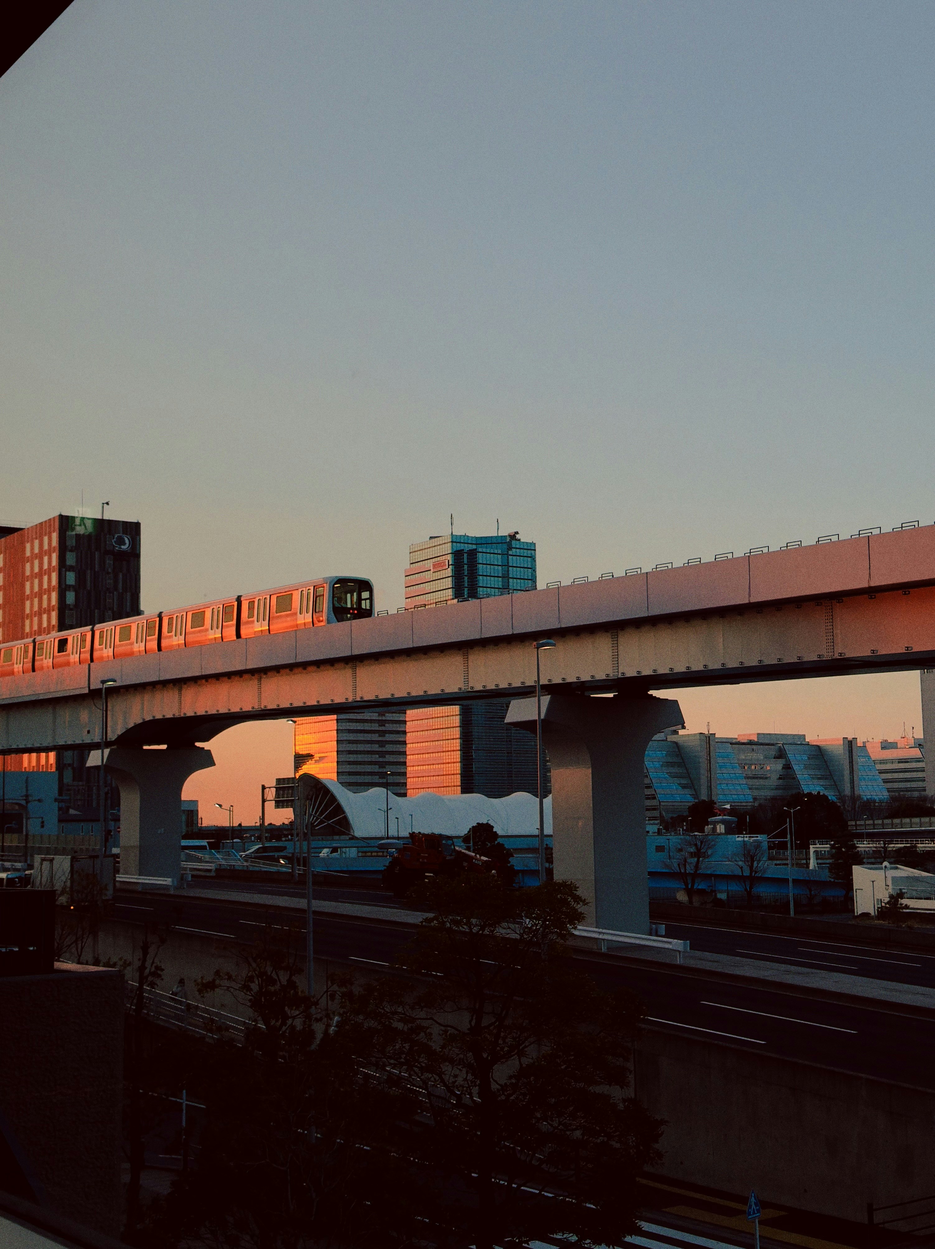 Monorail train traveling over elevated track at sunset