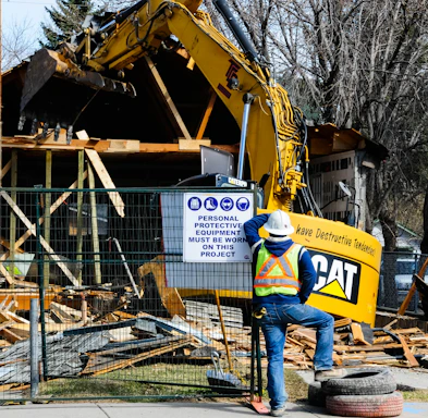 Demolition crew works on a house with heavy machinery.