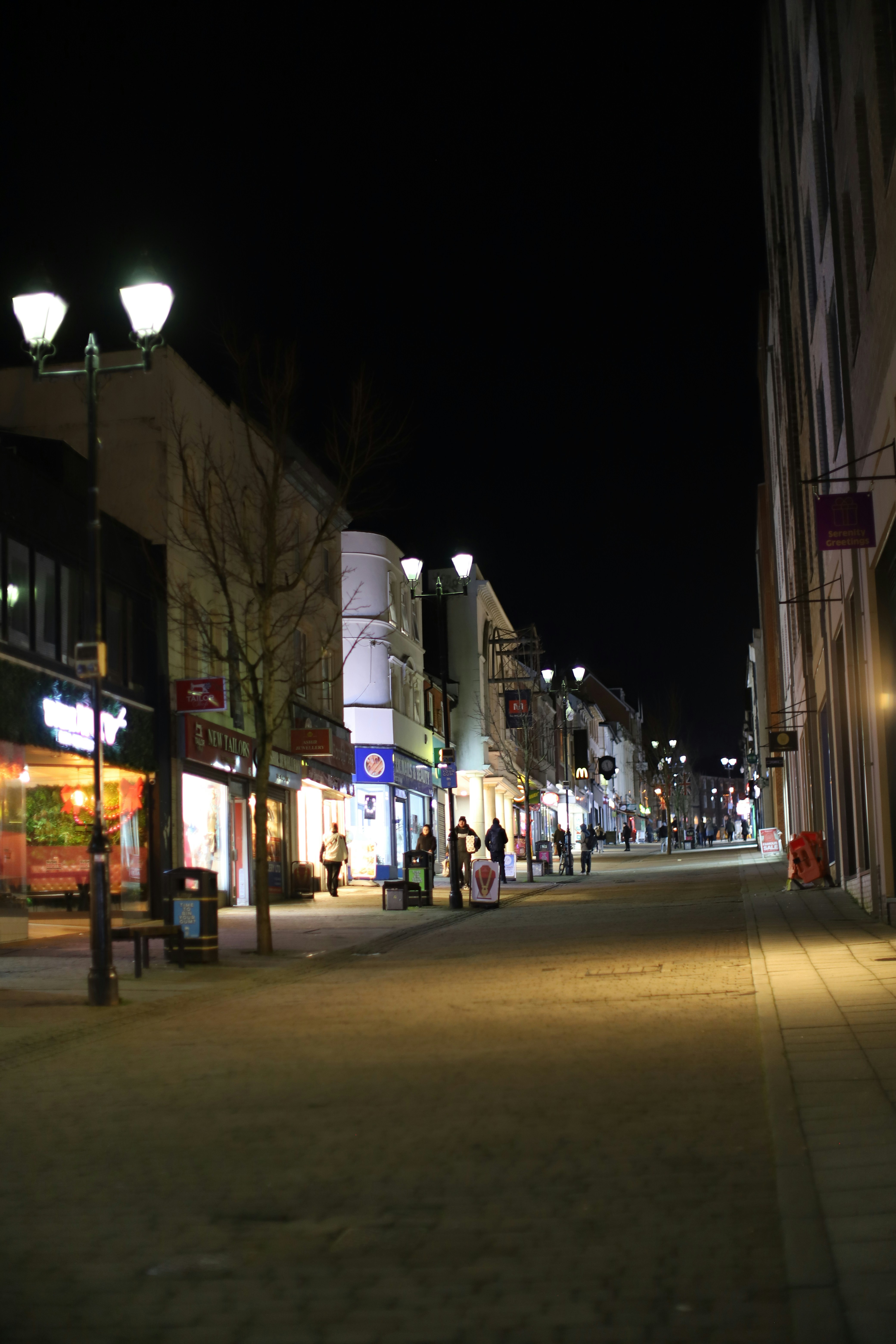 Streetlights illuminate a quiet town street at night.