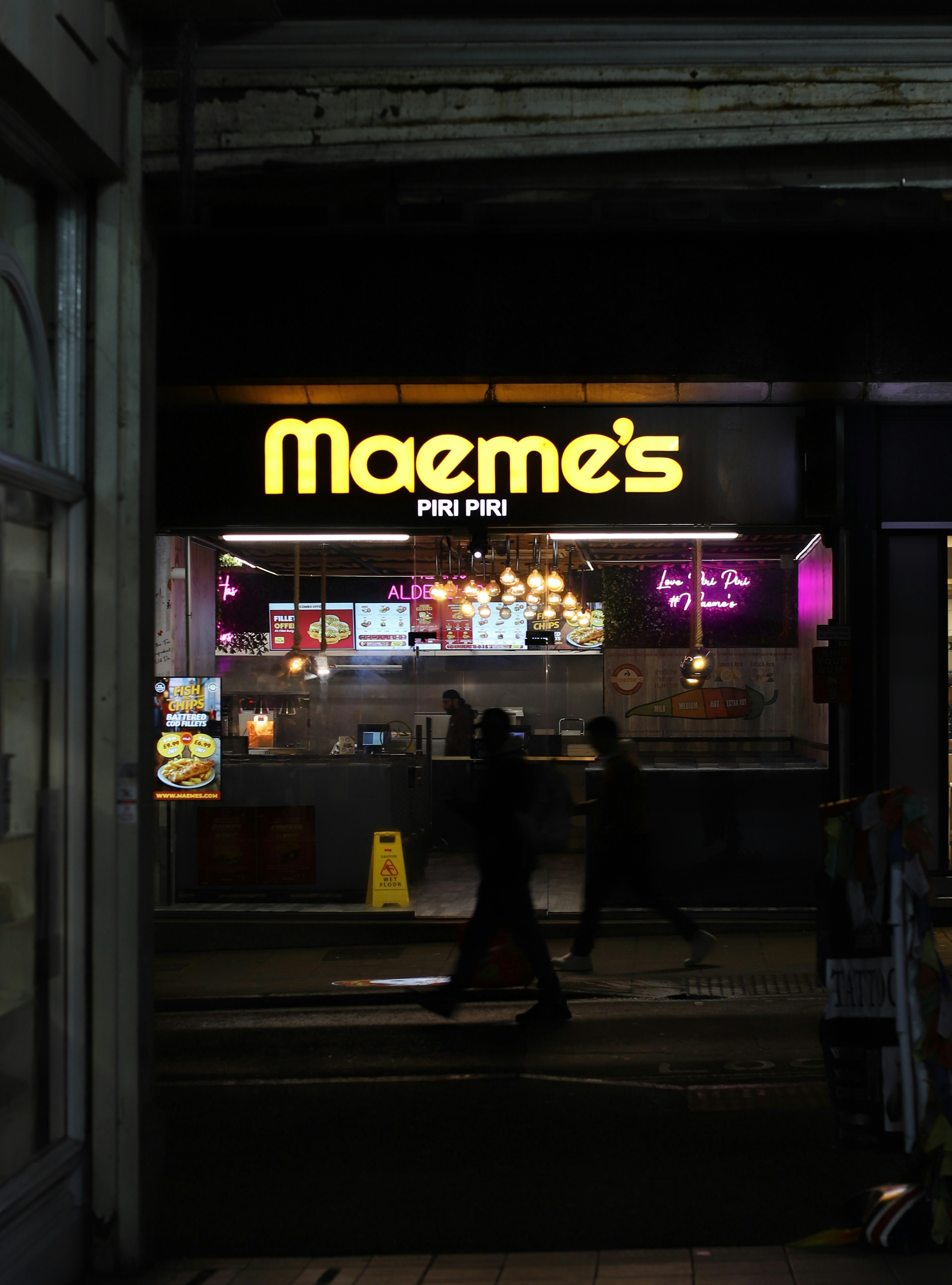 Maeme's piri piri restaurant at night with people walking