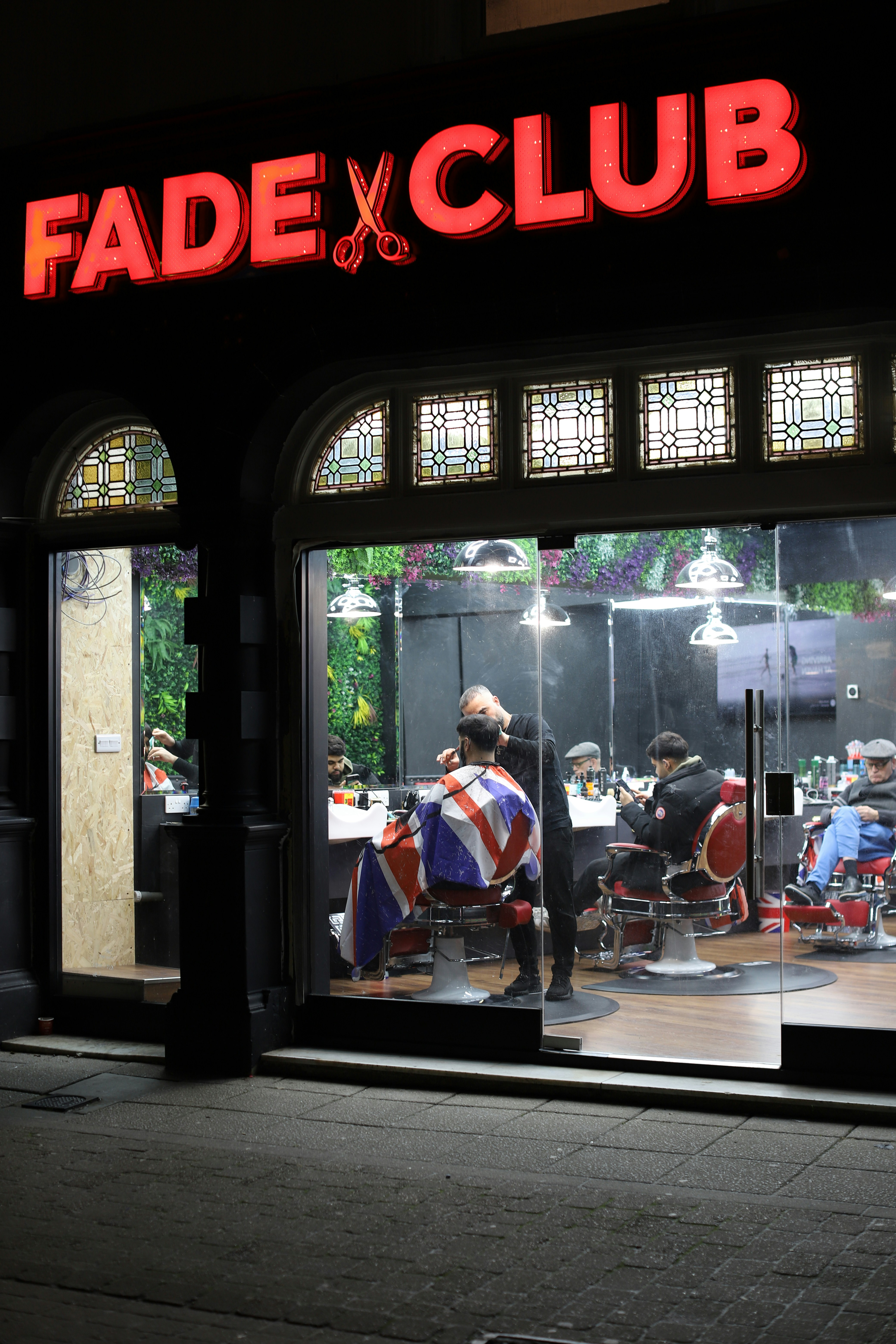 Barbershop interior with clients getting haircuts at night