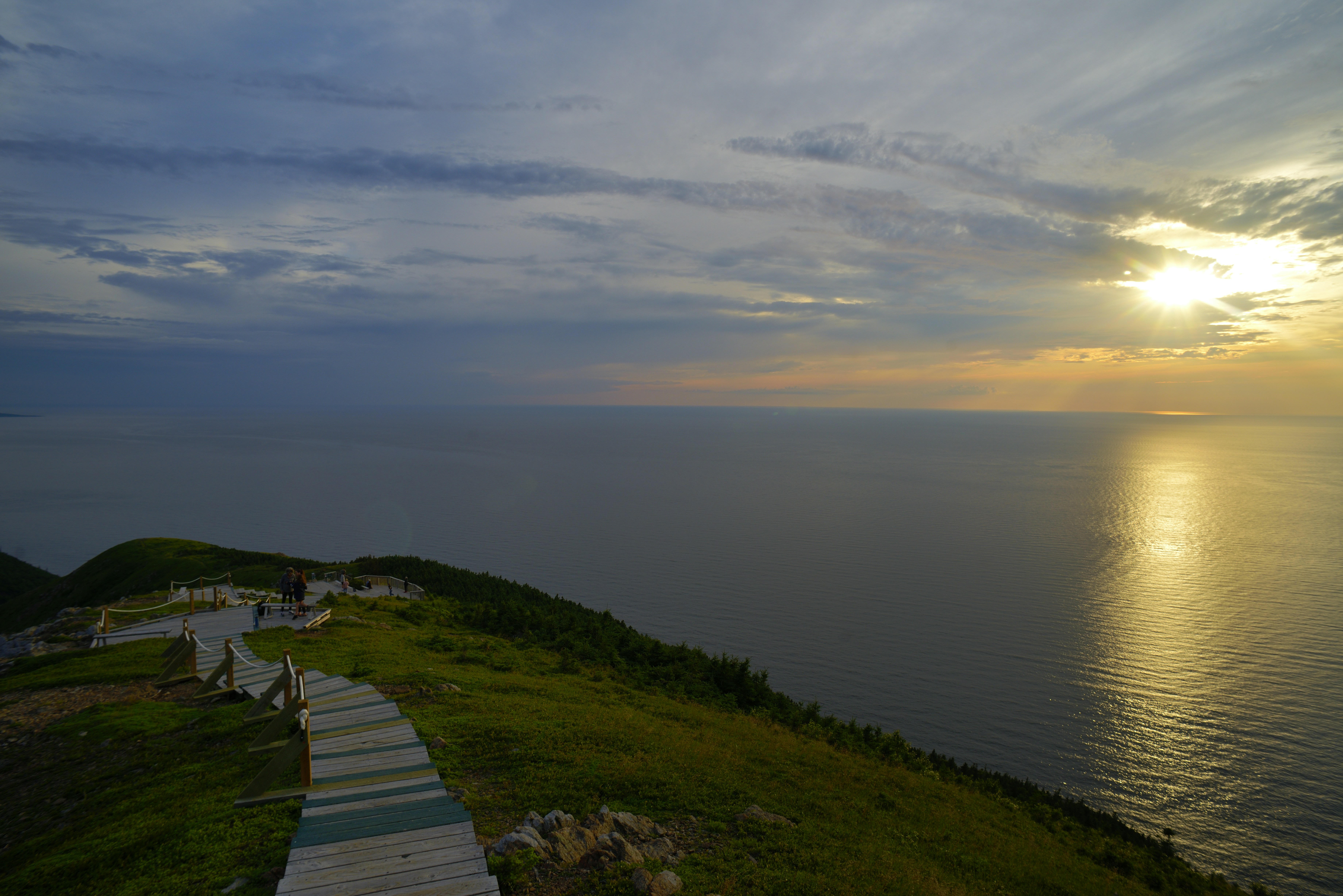 Ocean view from a grassy cliff at sunset