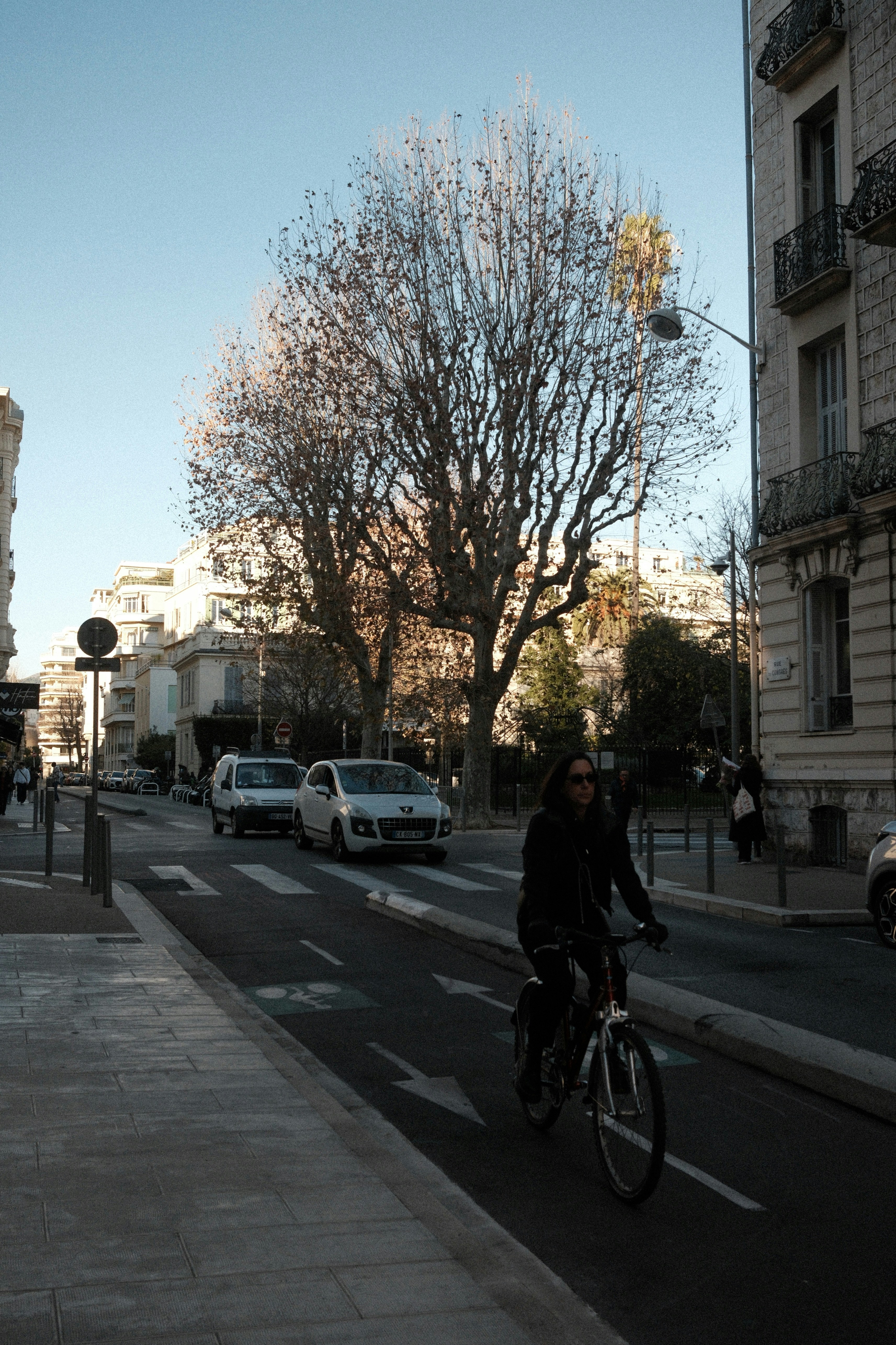 Cyclist rides on a city street with cars and buildings