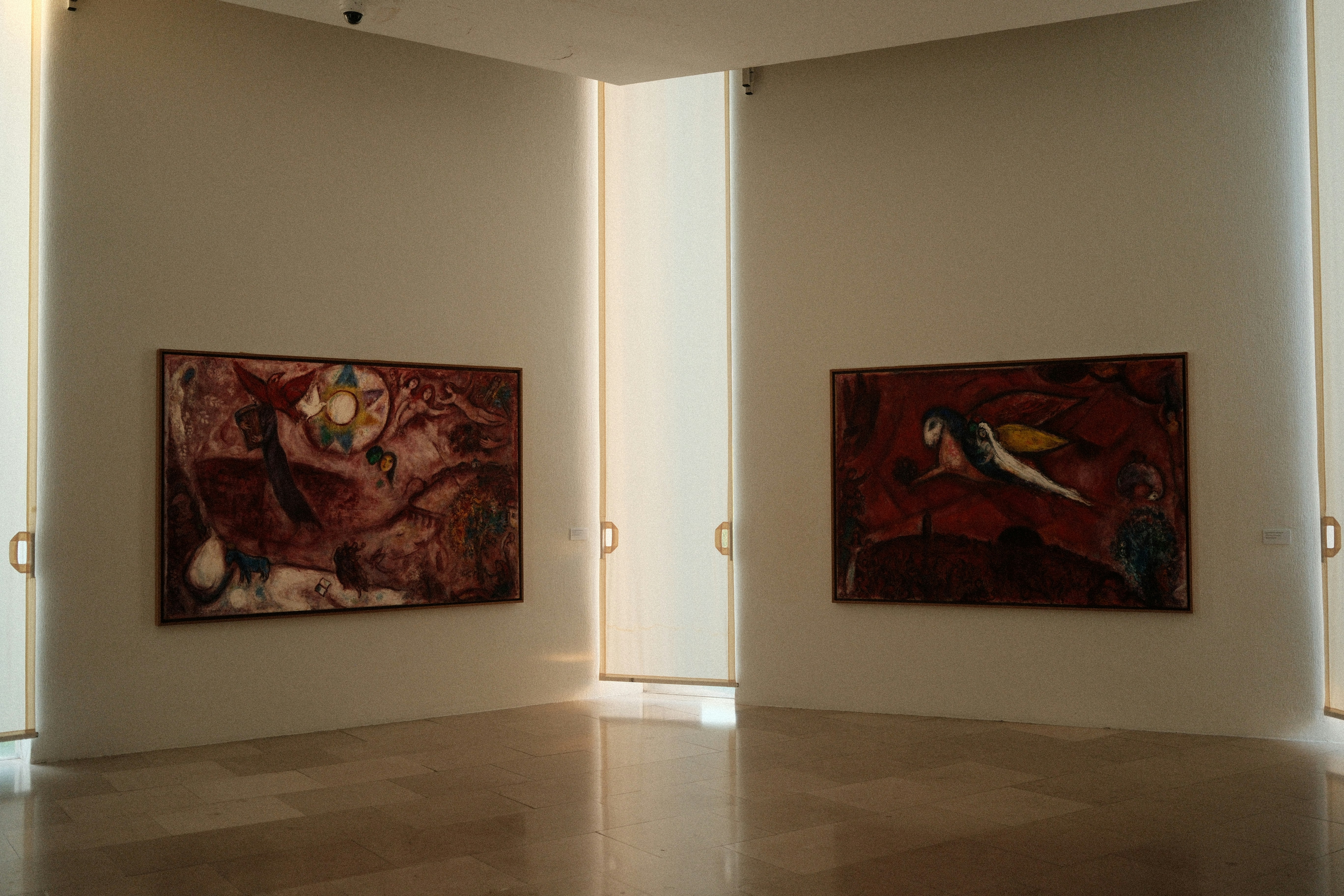 Two abstract paintings hang on museum walls.