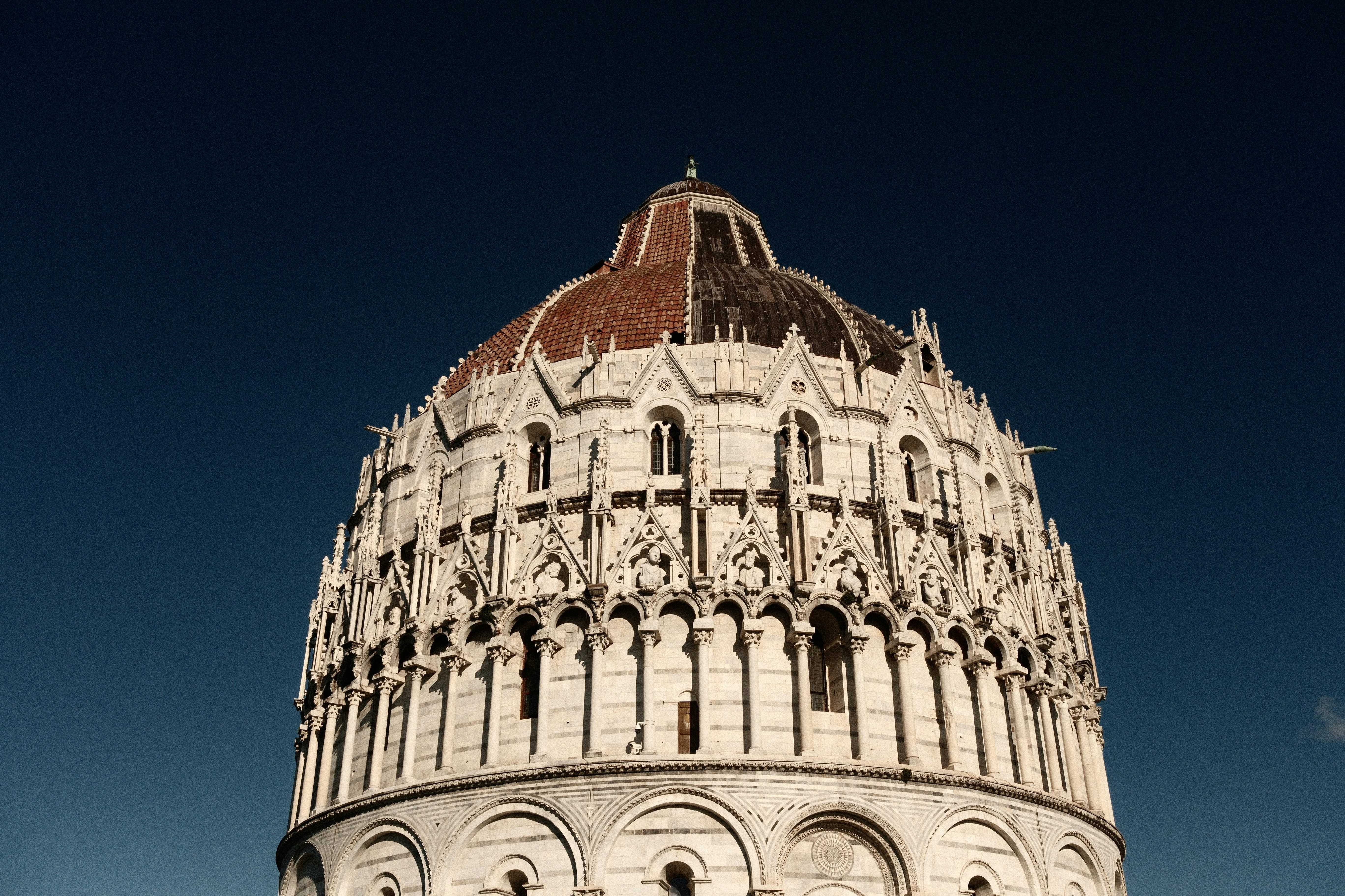 The pisa baptistery against a clear blue sky.