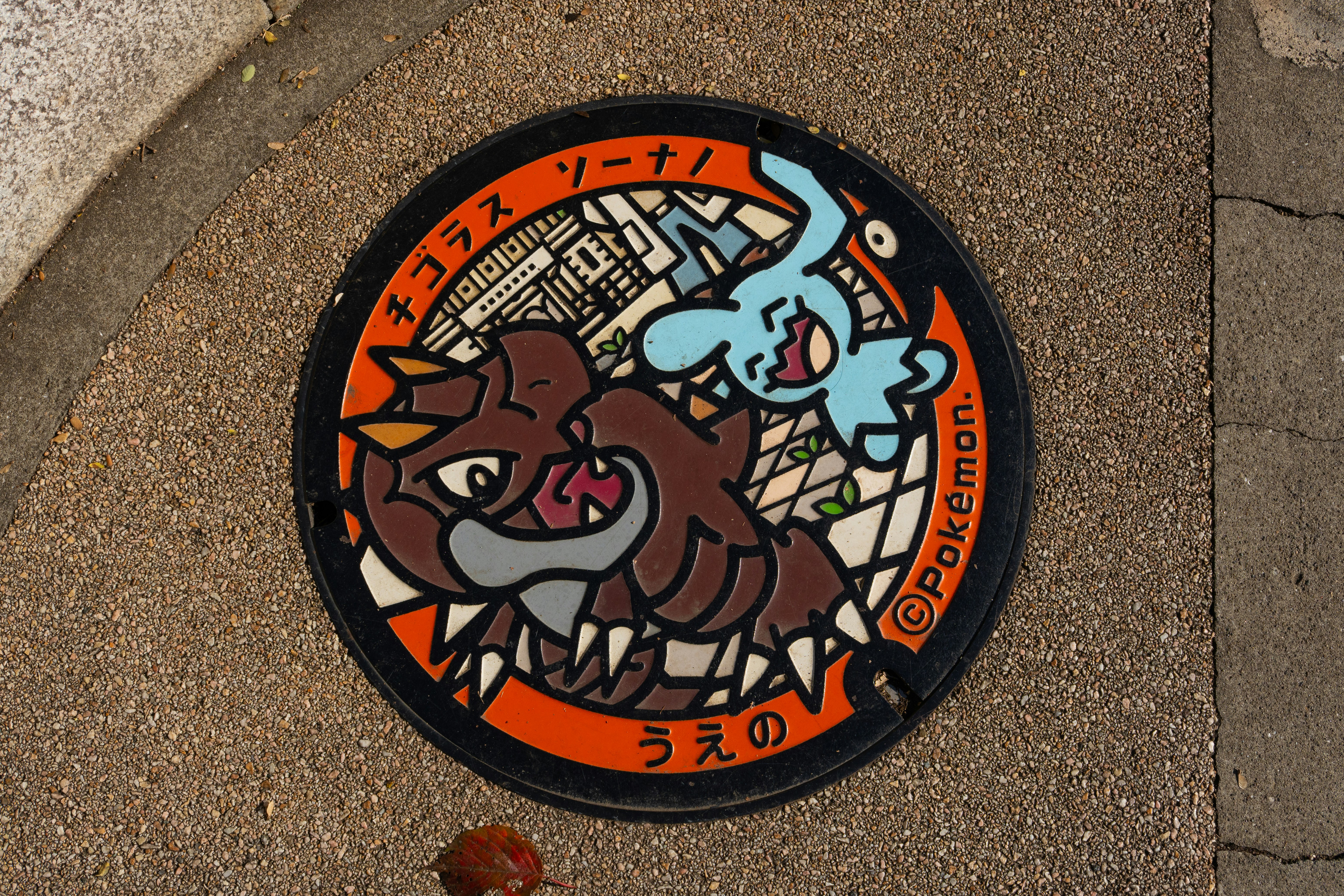 Tapa de alcantarilla Pokémon con caracteres marrones y azules