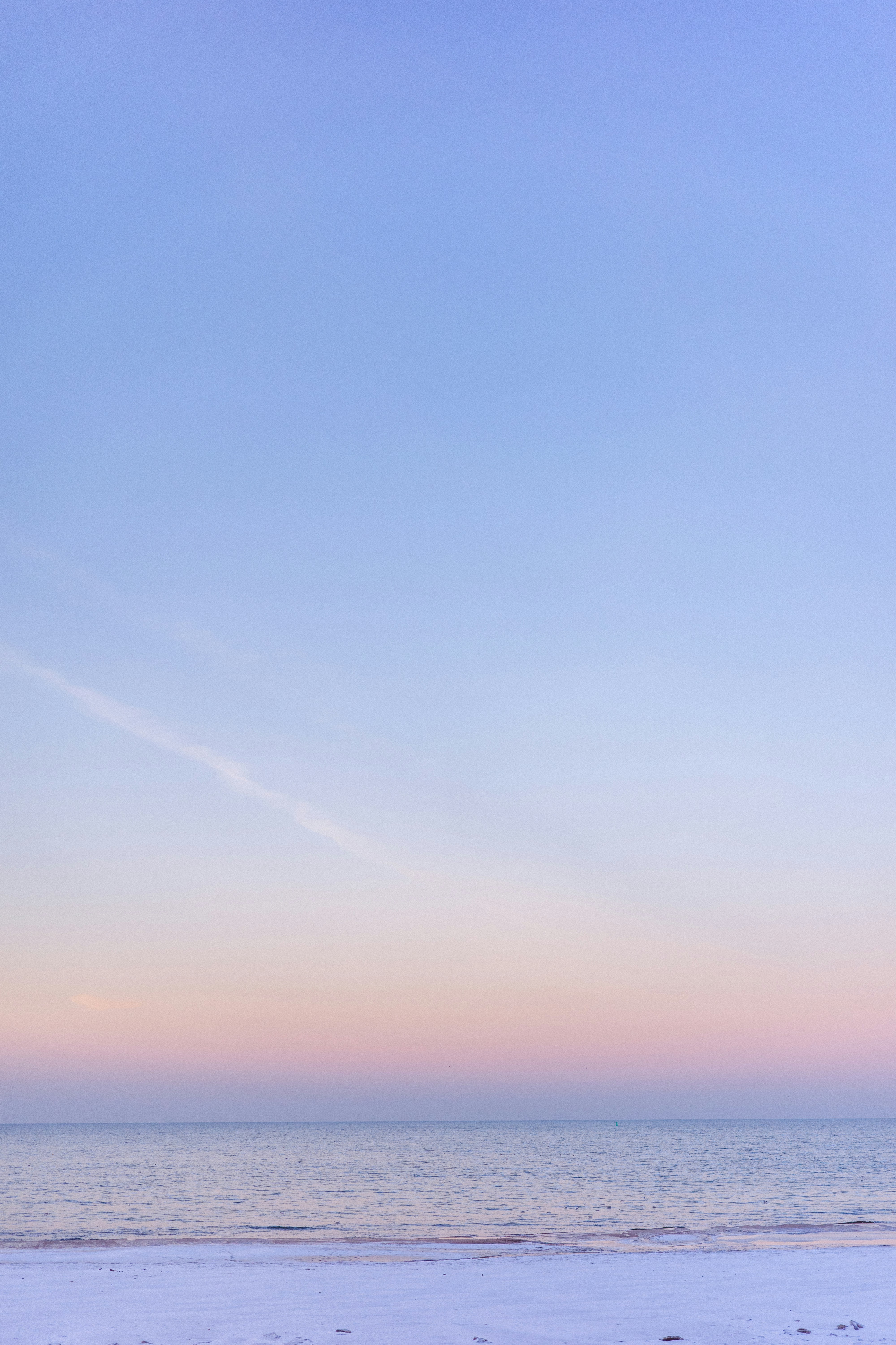 Pastel sky over a calm ocean and snowy beach