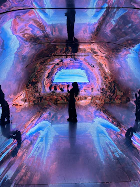 Person silhouetted in a colorful, abstract digital art installation