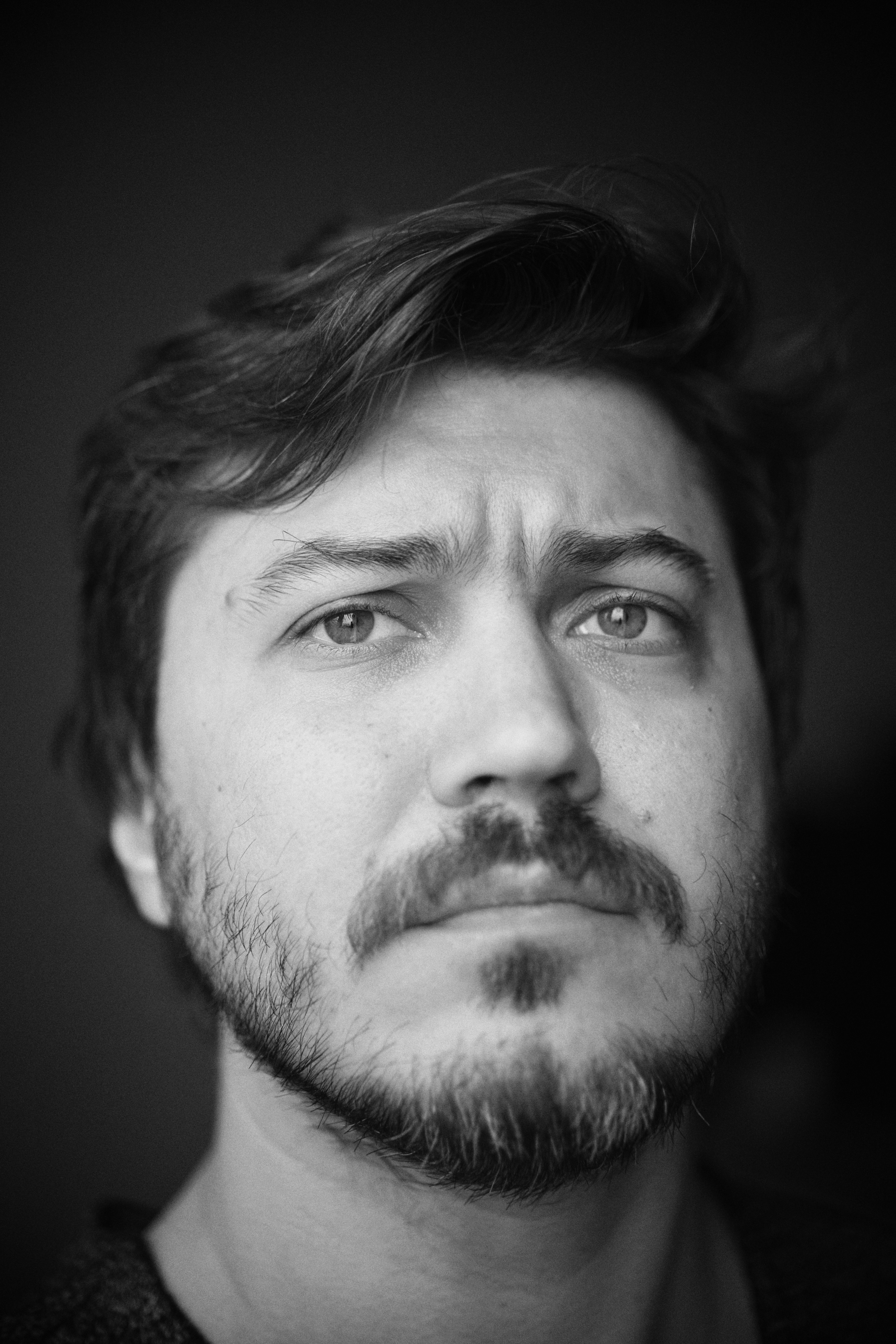 A man with a beard and mustache looks up.