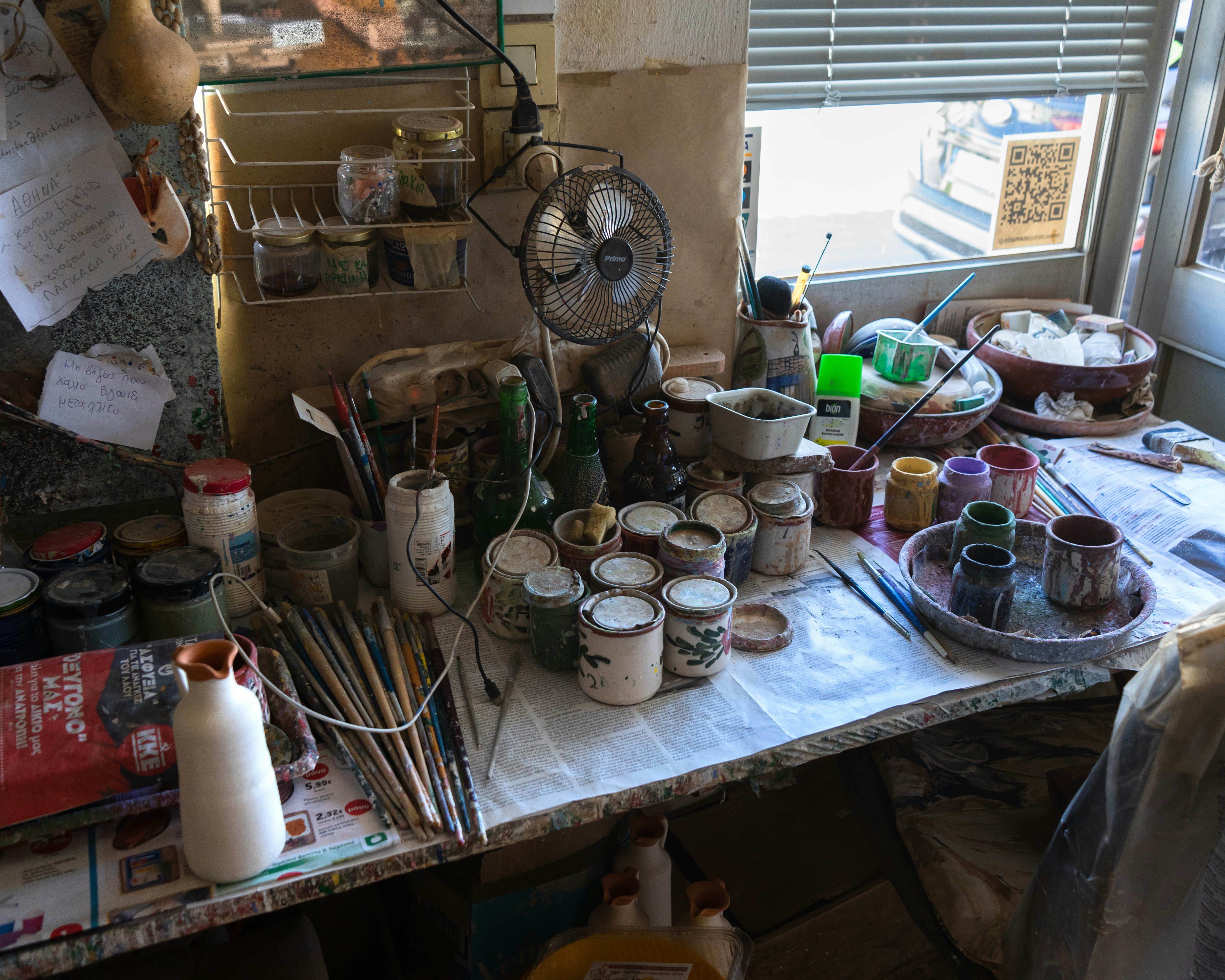 Art studio table with paints, brushes, and pottery.