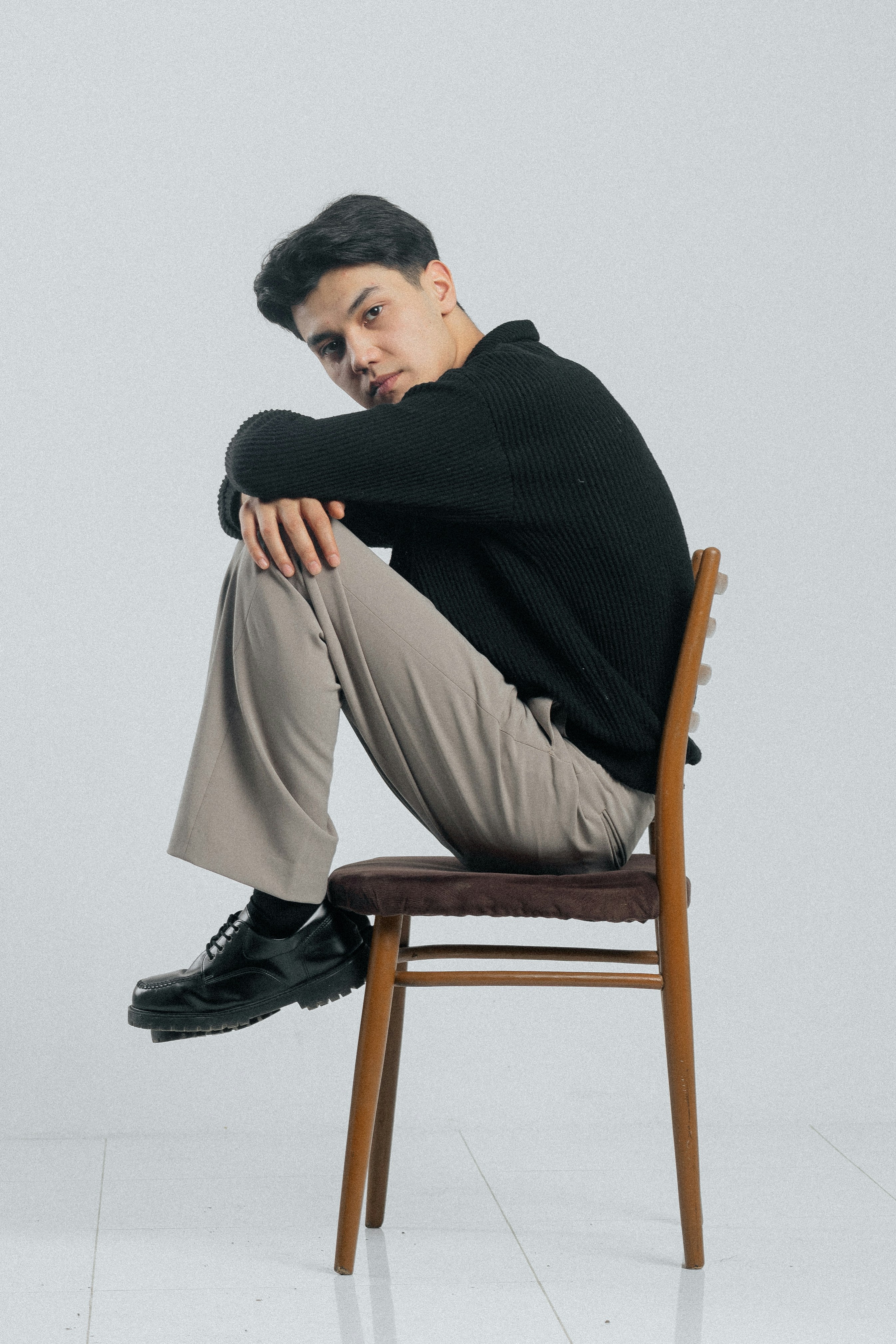 Young man sitting on a chair with knees drawn up