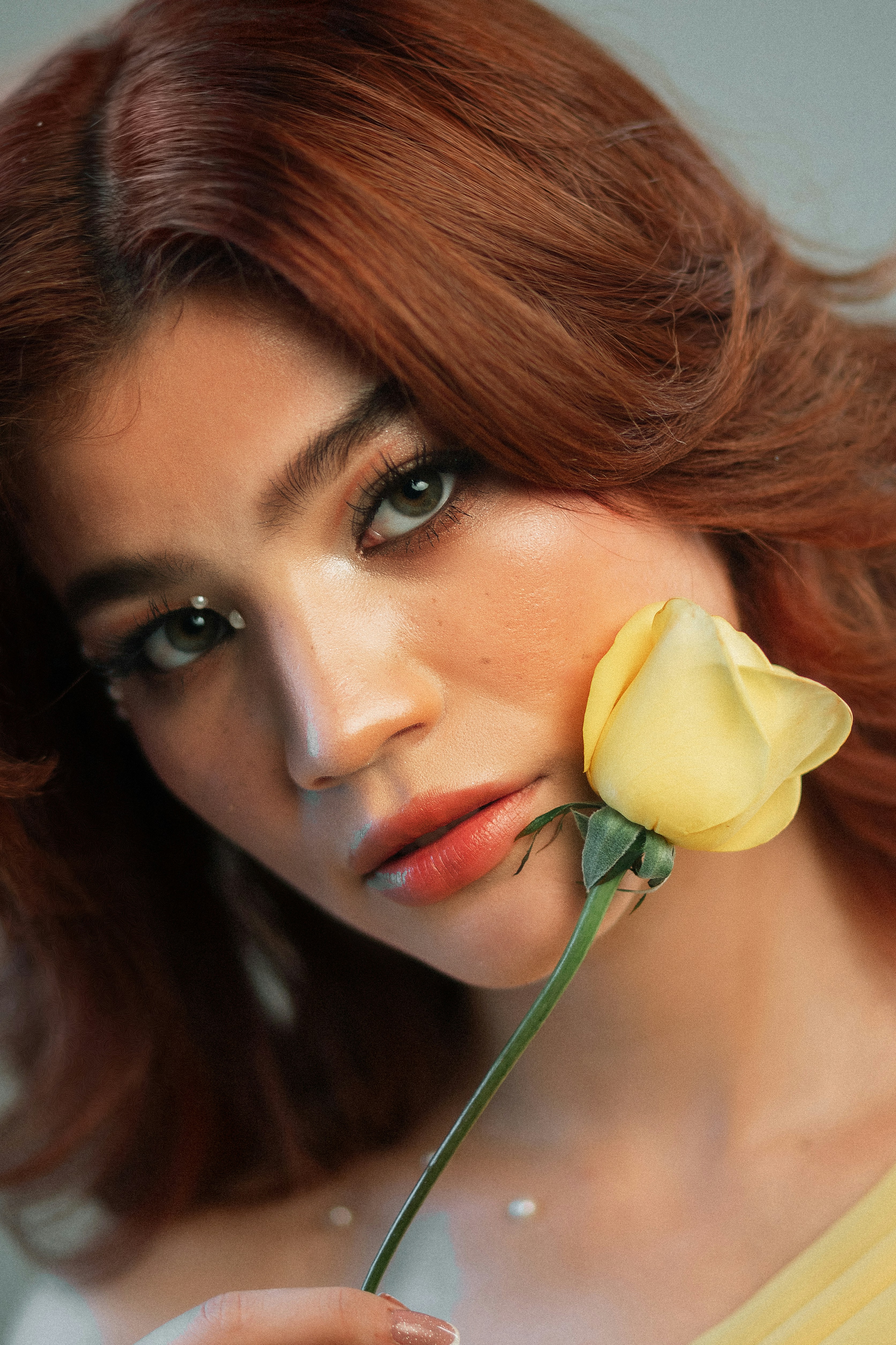 Frau mit roten Haaren, die eine gelbe Rose hält