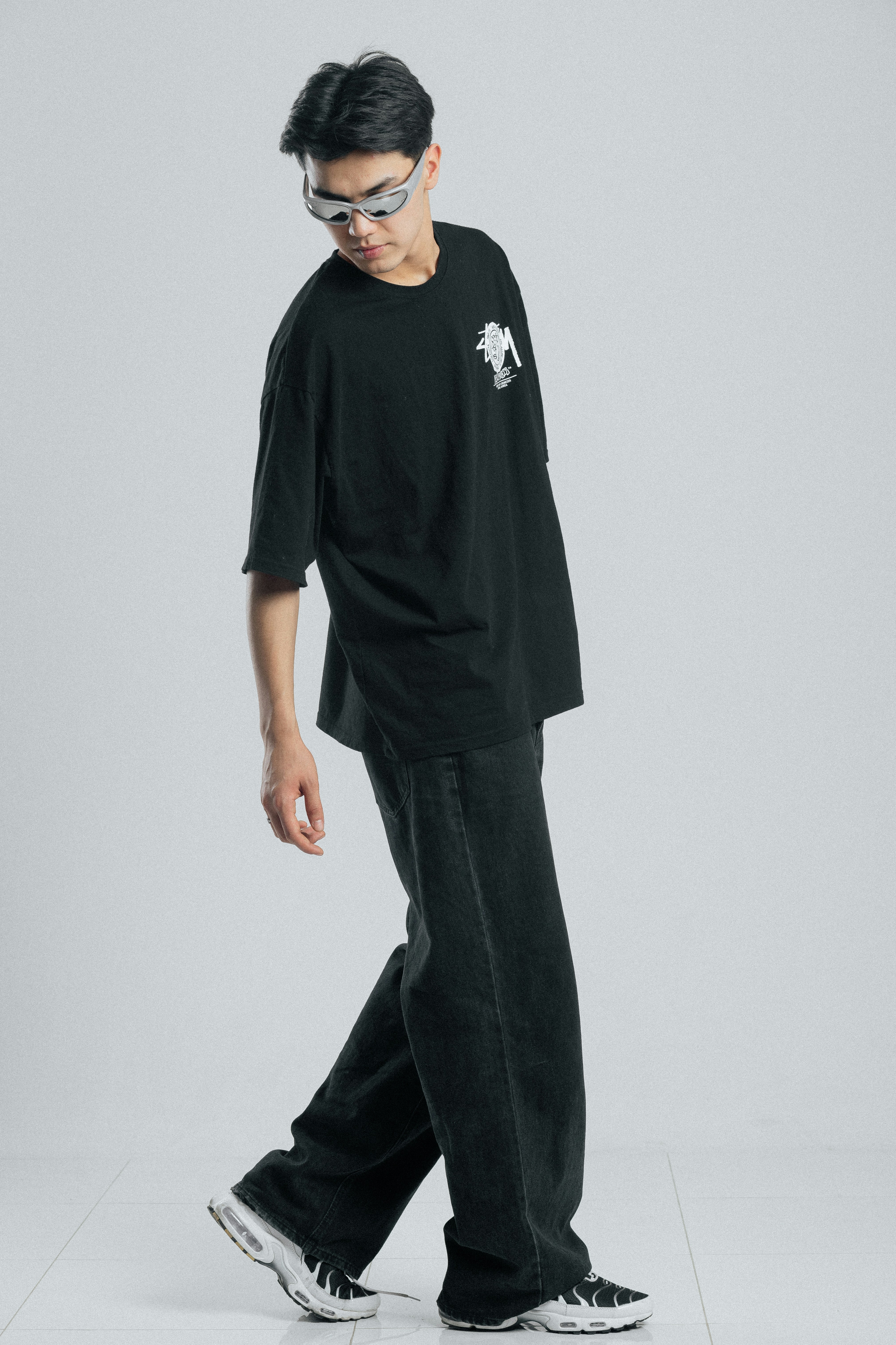 Young man in black t-shirt and jeans walking.