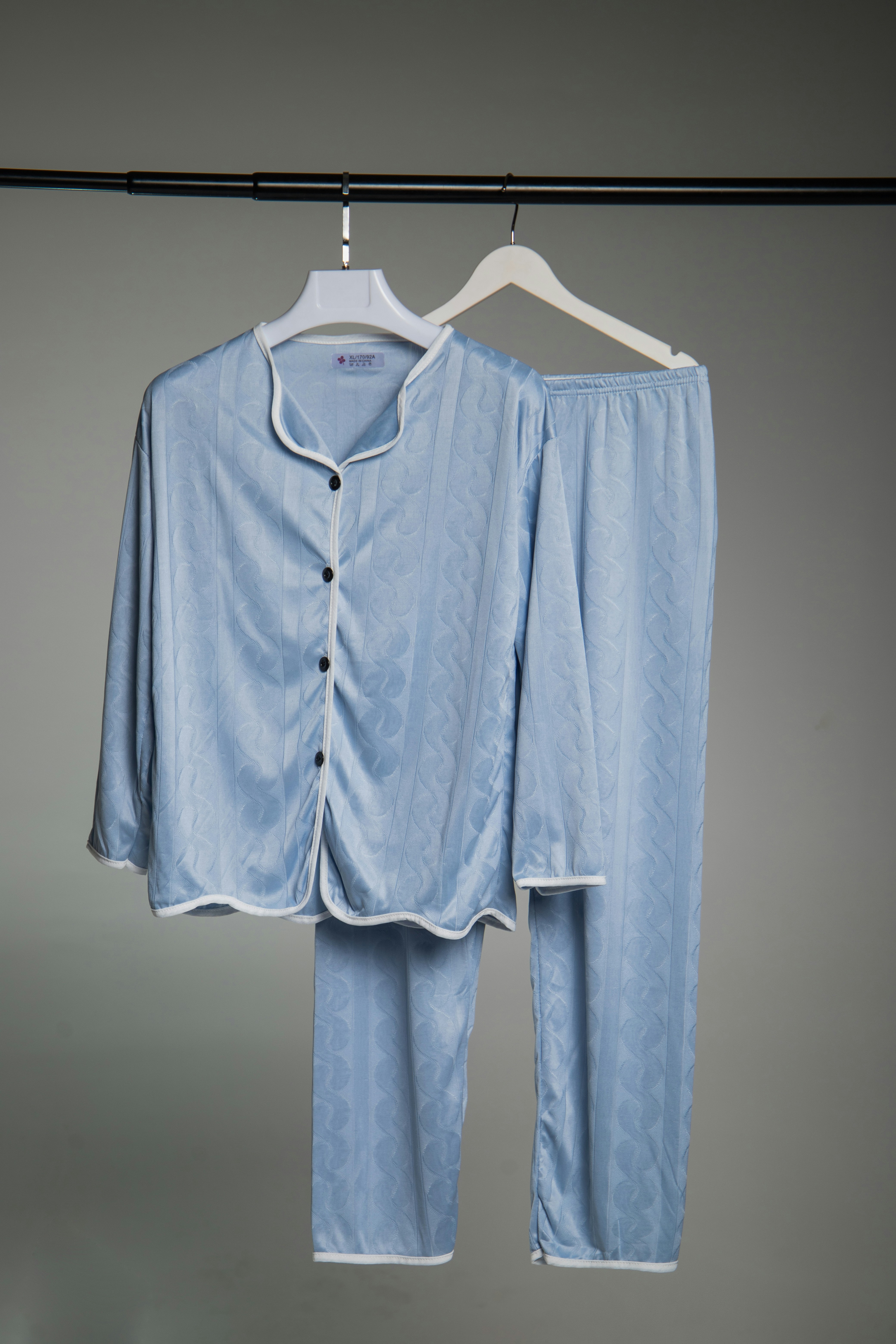 Light blue pajamas with white trim hanging on rack