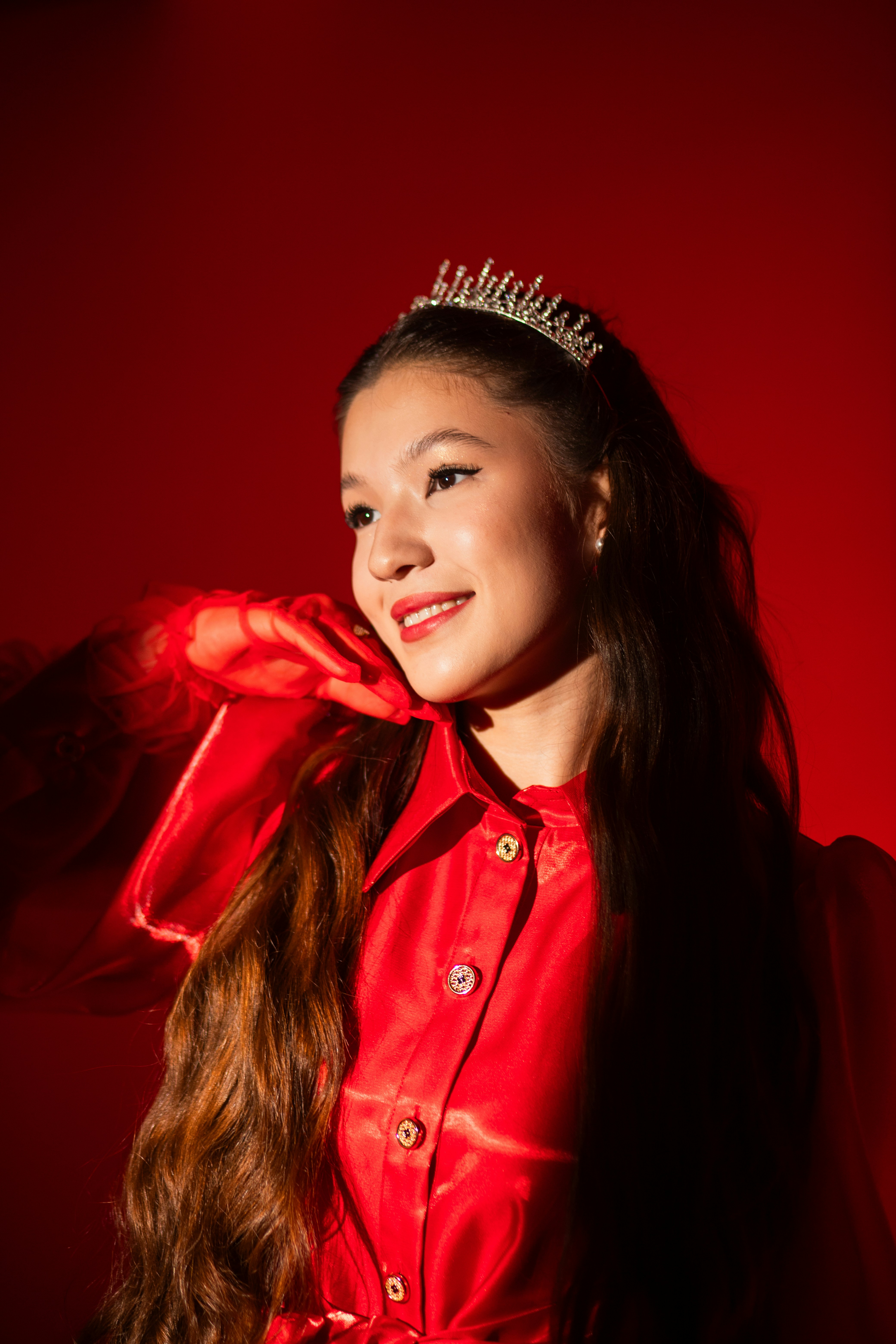 Young woman in a tiara and red dress smiles