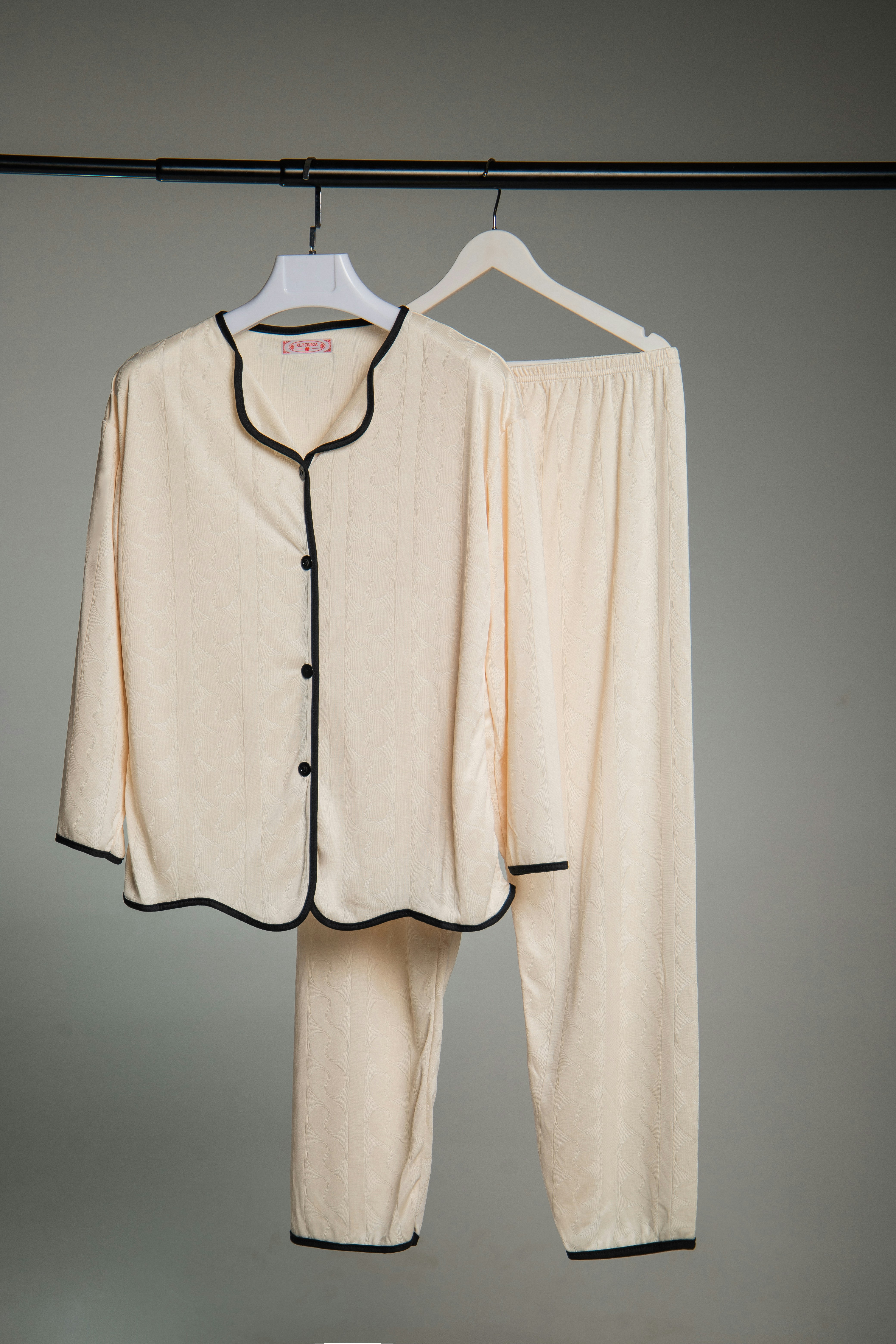 Cream colored pajamas with black trim hanging