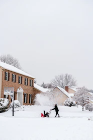 Person using snow blower in front of brick house