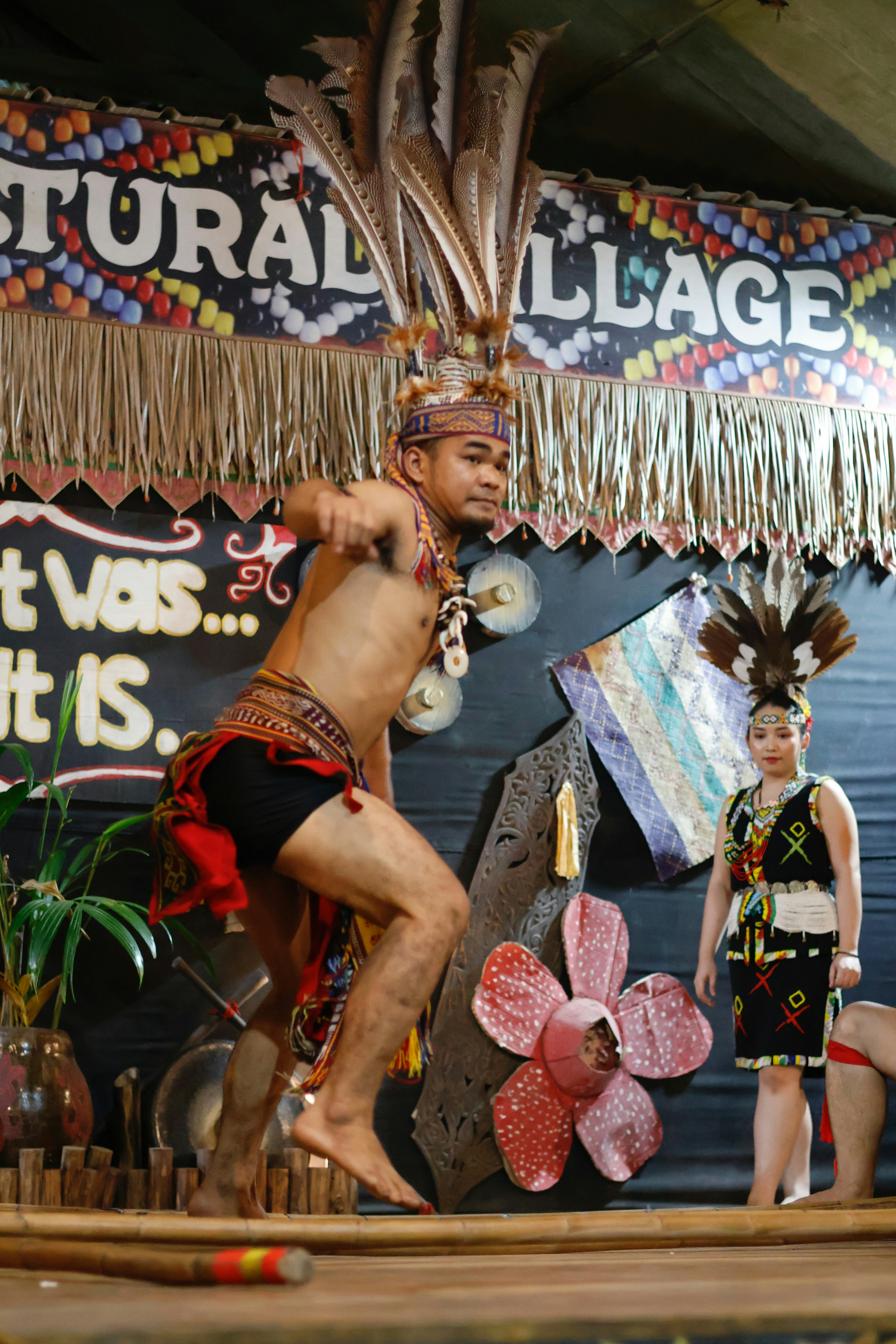 伝統的な衣装を着た男性が女性と共にステージで踊る。