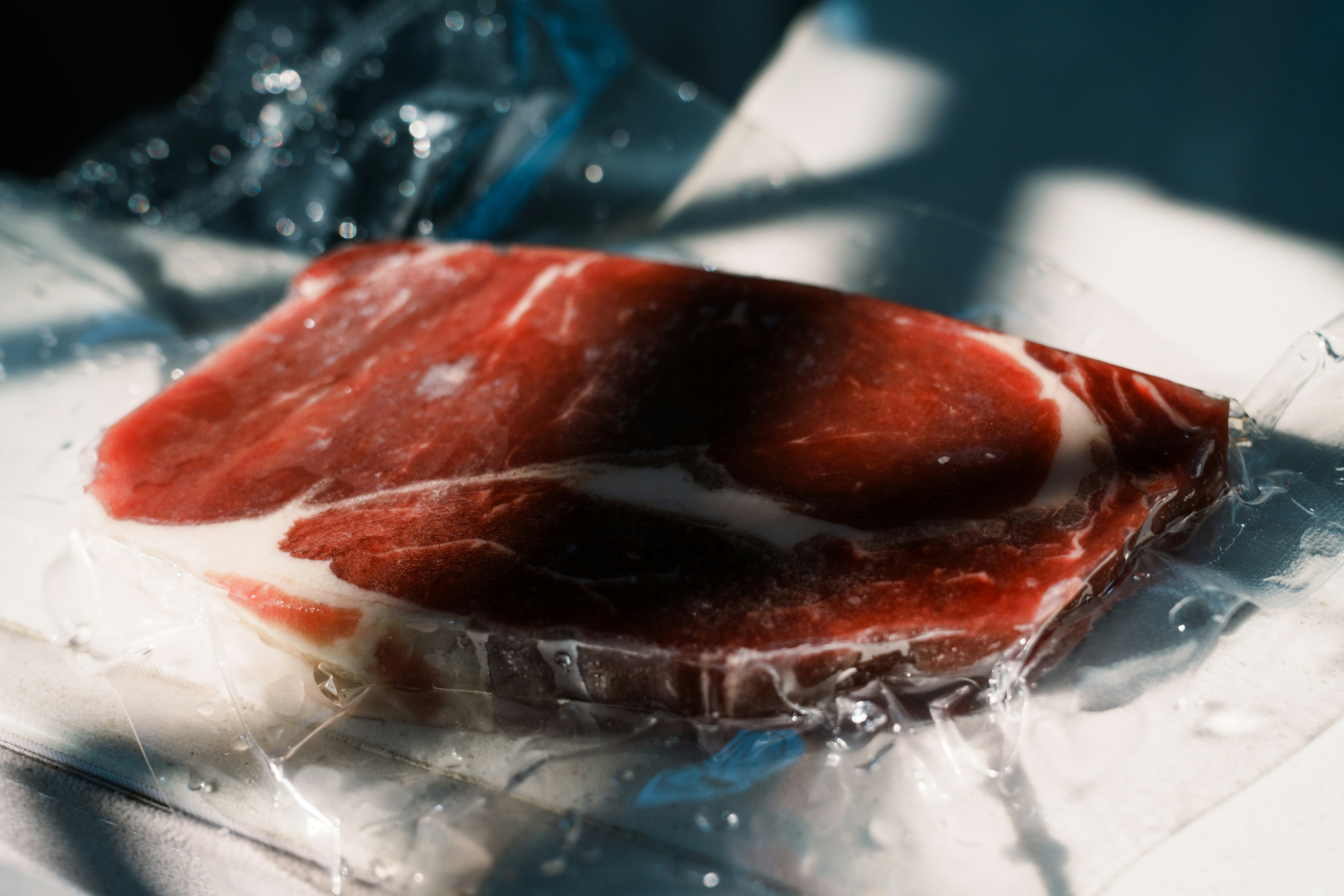 Raw marbled steak vacuum-sealed in plastic