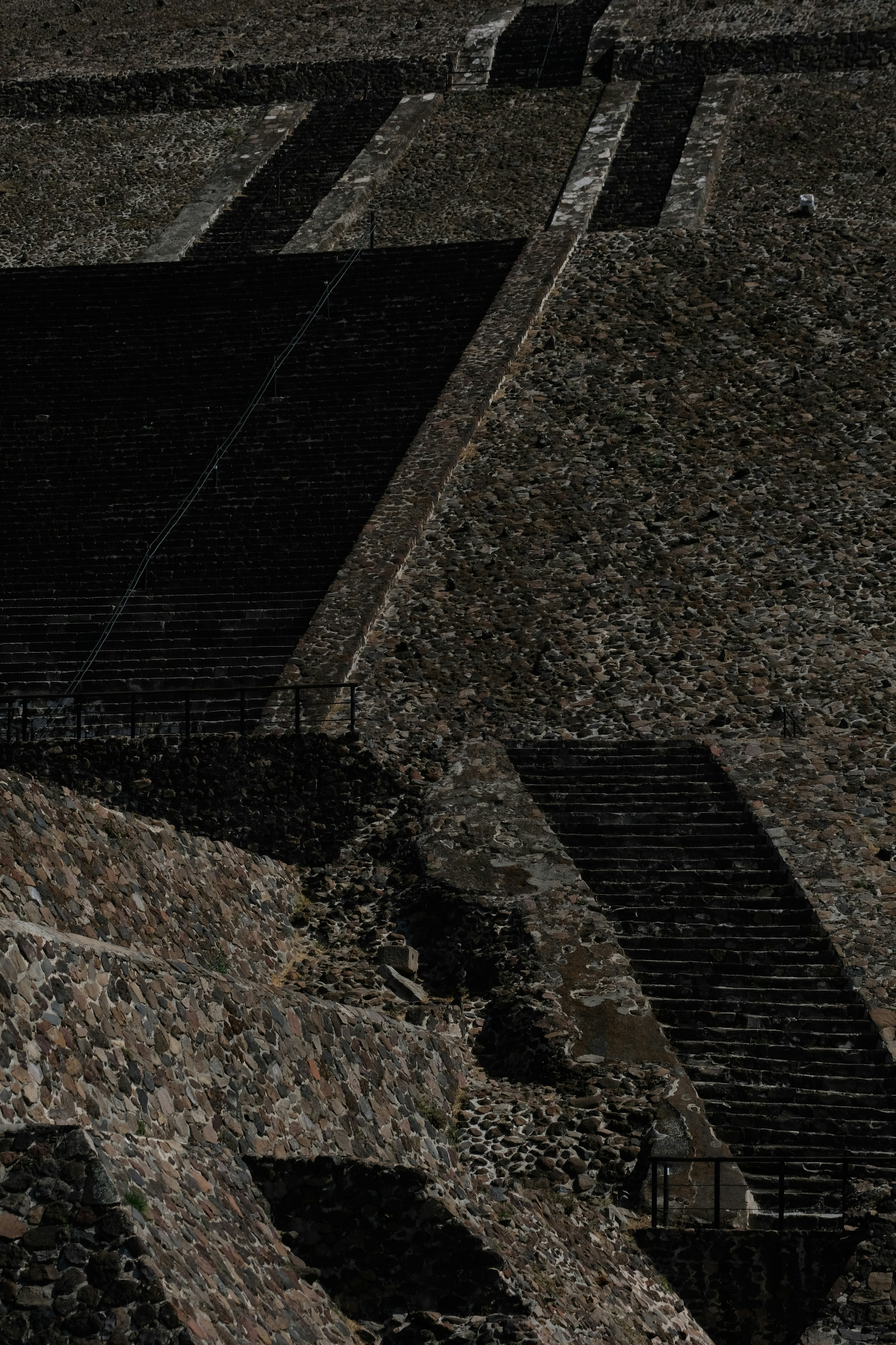 Stone steps ascend ancient pyramids under harsh sunlight.