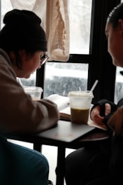 Two people studying at a table with drinks
