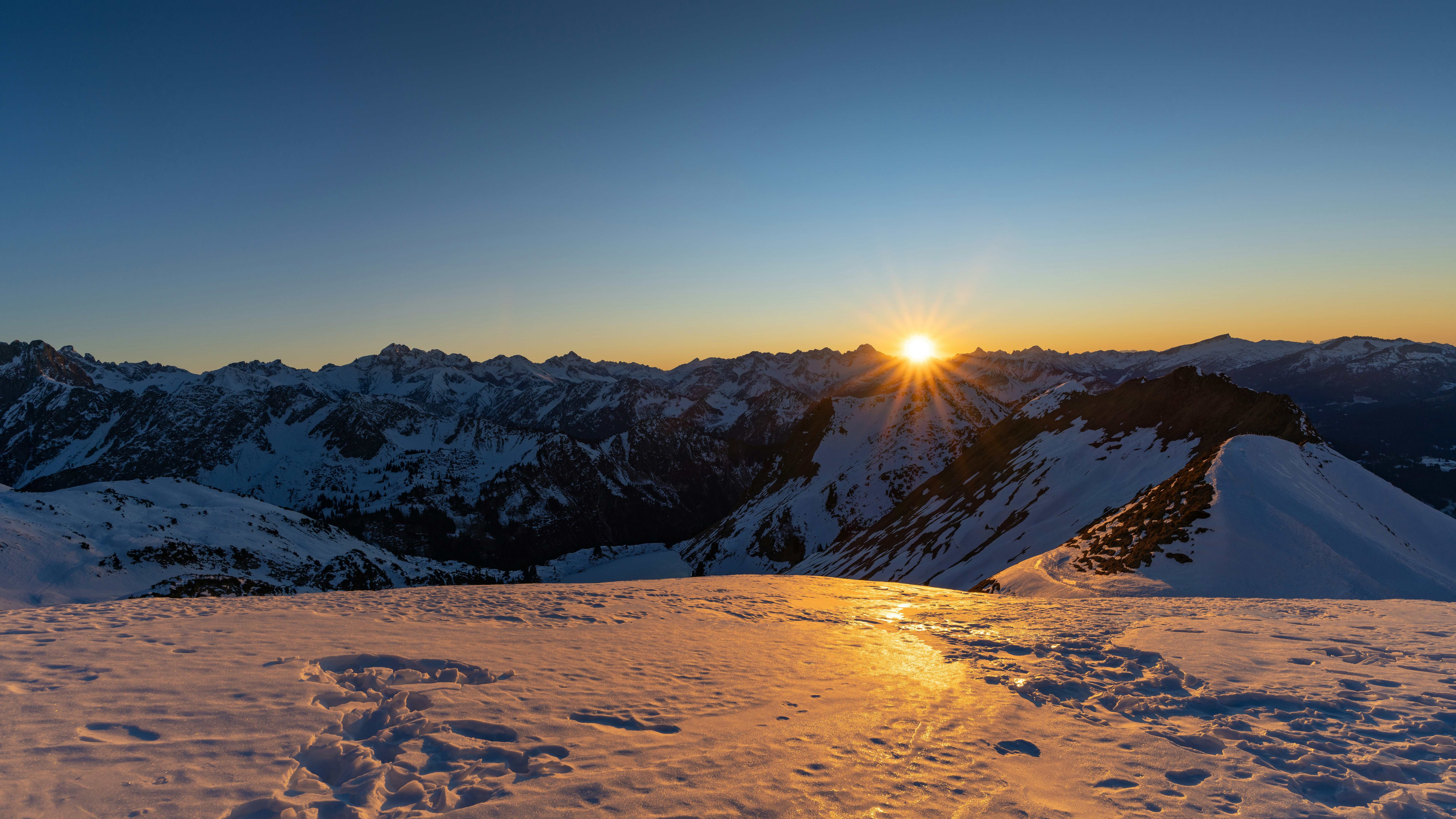 Sonnenaufgang über verschneiten Berggipfeln bei Tagesanbruch