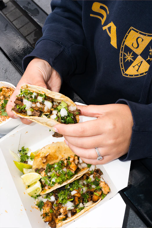 Person holding a street taco filled with meat and onions