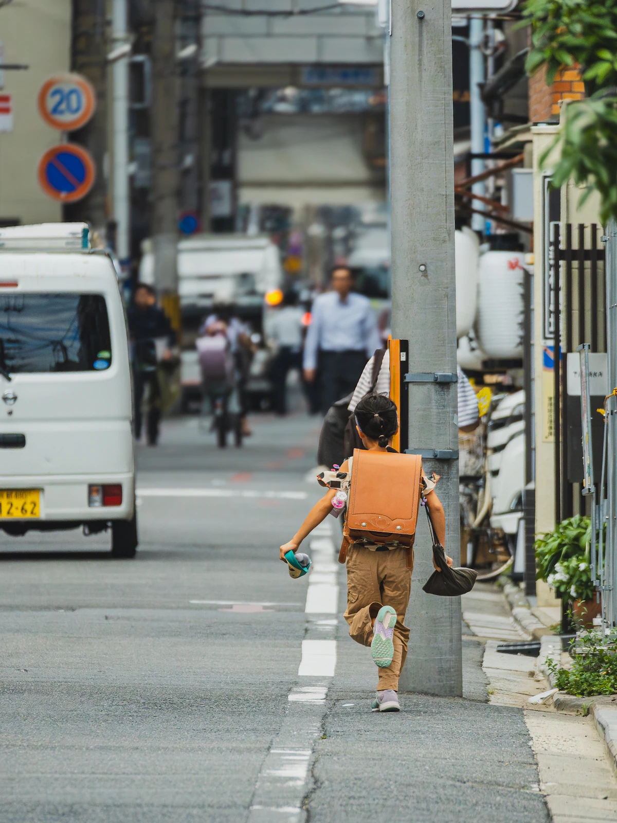 Anak berransel berlari di jalan kota.