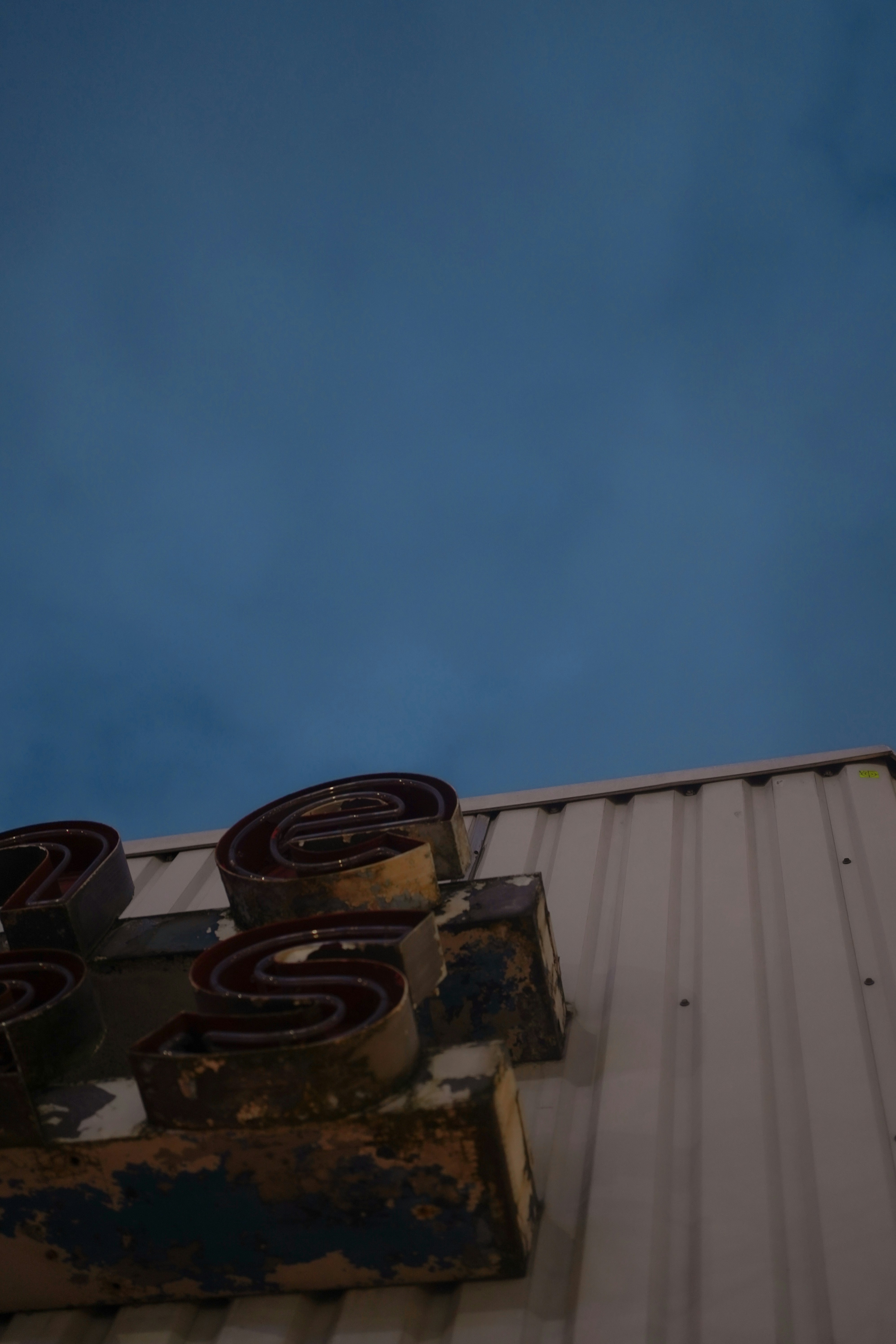 Carteles de neón oxidados en una pared de chapa ondulada