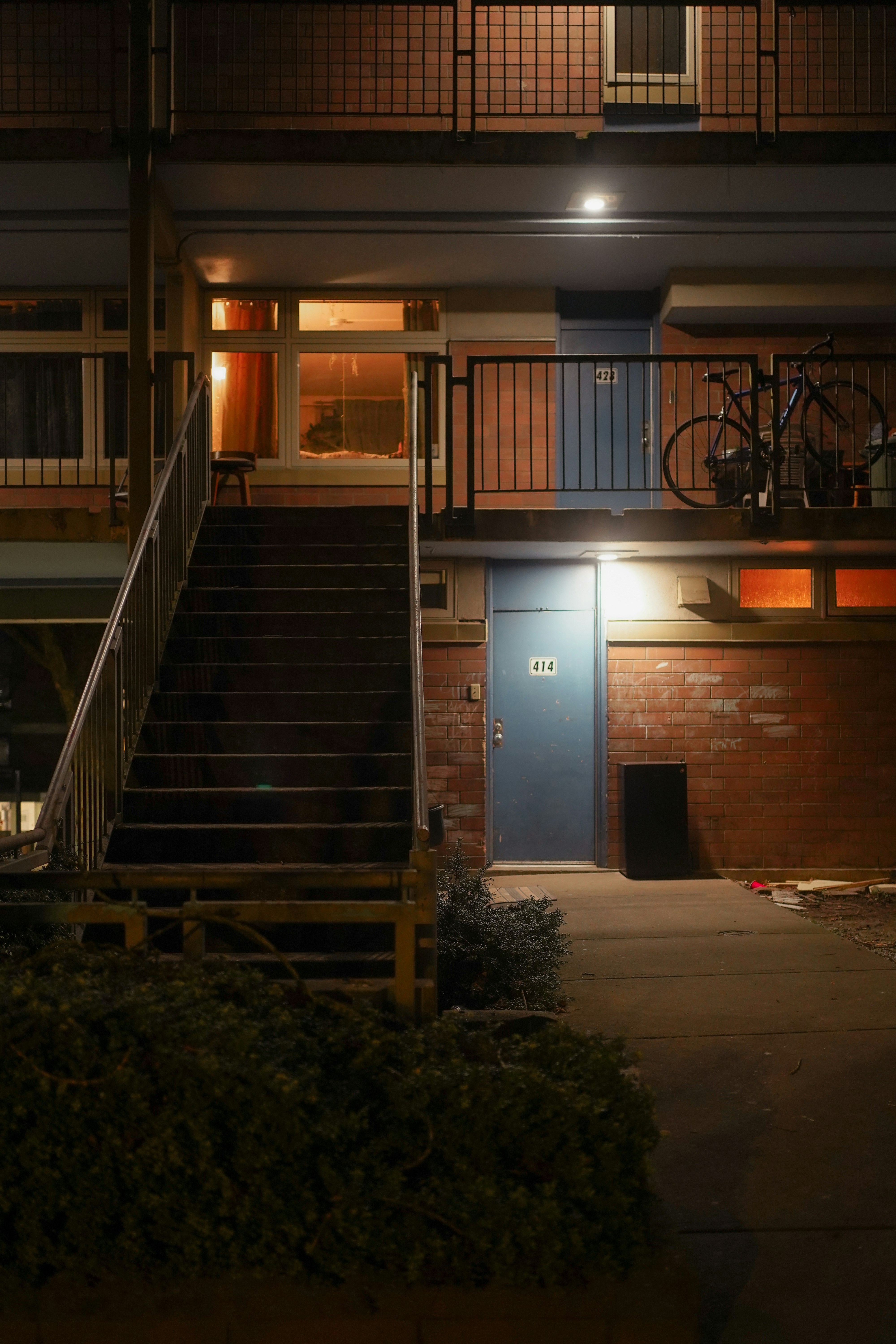 Apartment building exterior at night with stairs and balcony.