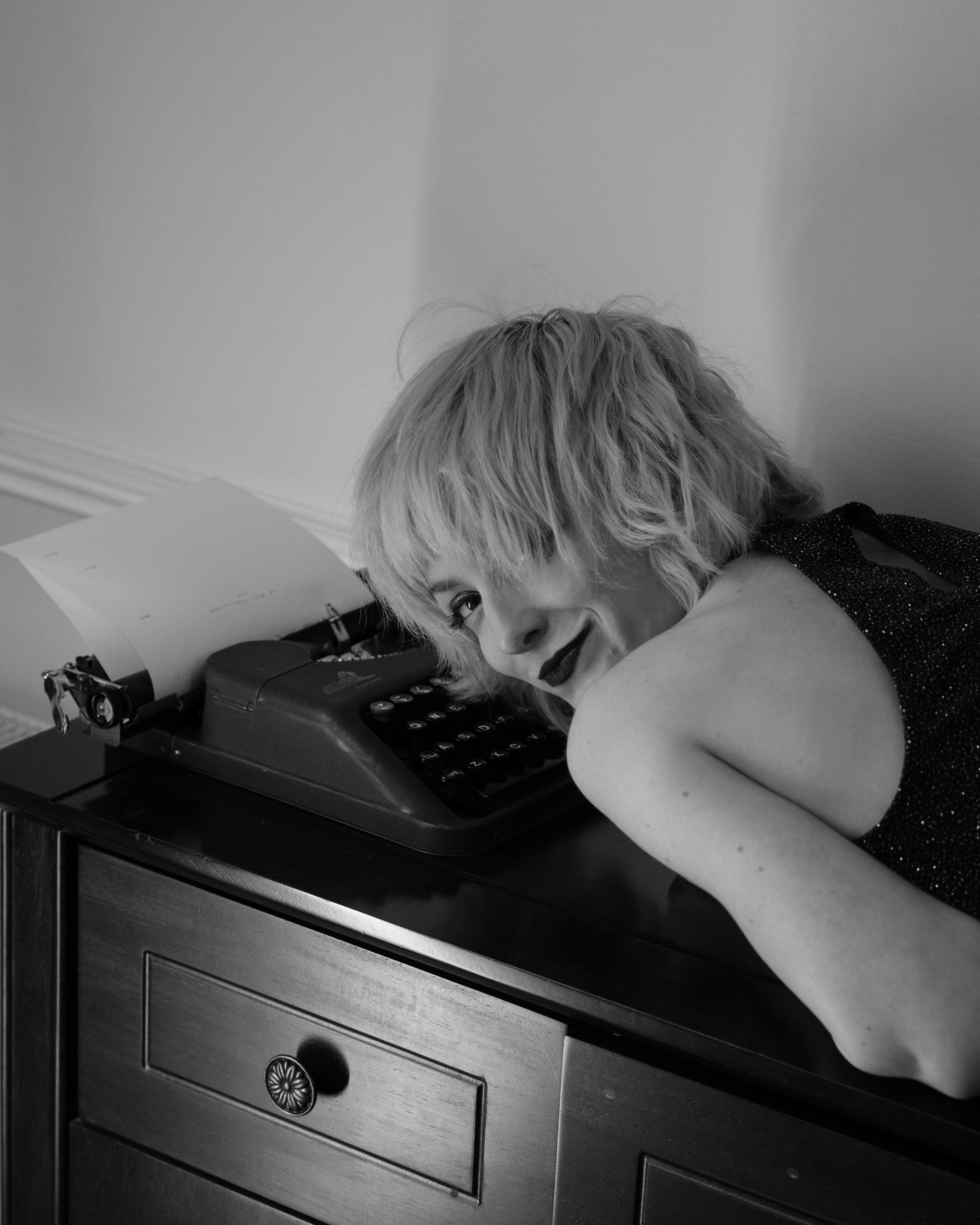 Woman leans over antique typewriter on a dresser