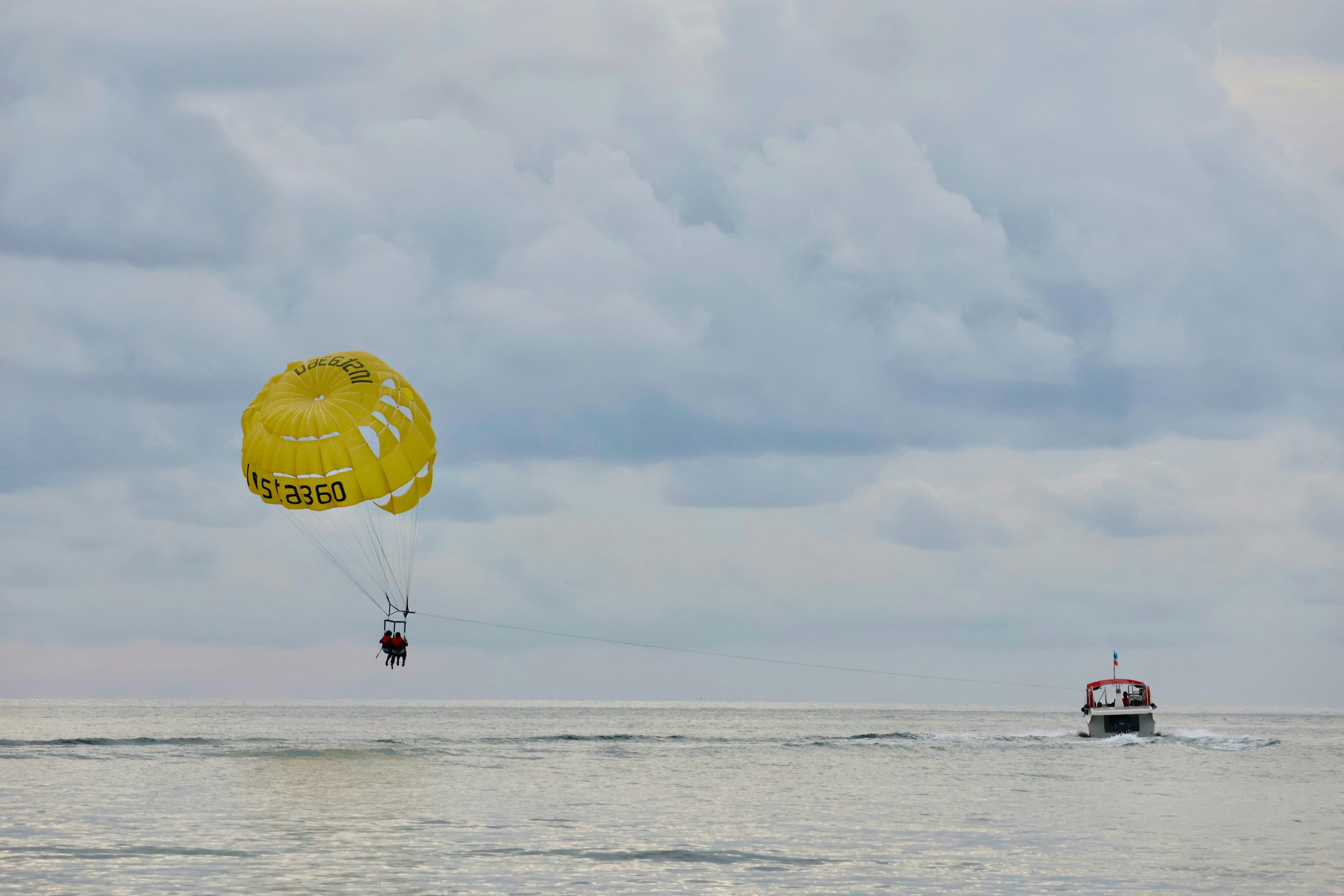 Parasailing over the ocean with a boat in distance