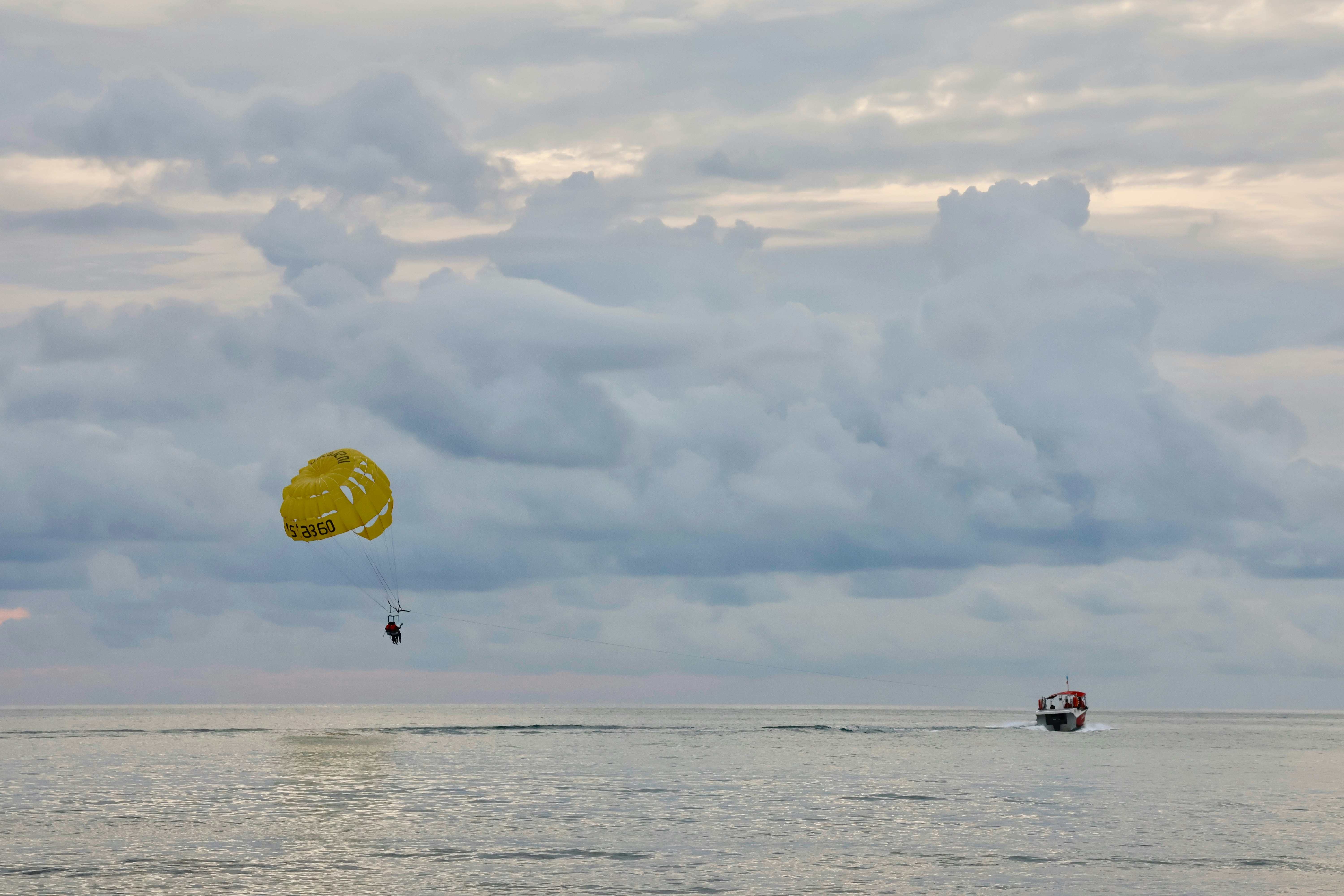 Yellow parachute with person over the ocean