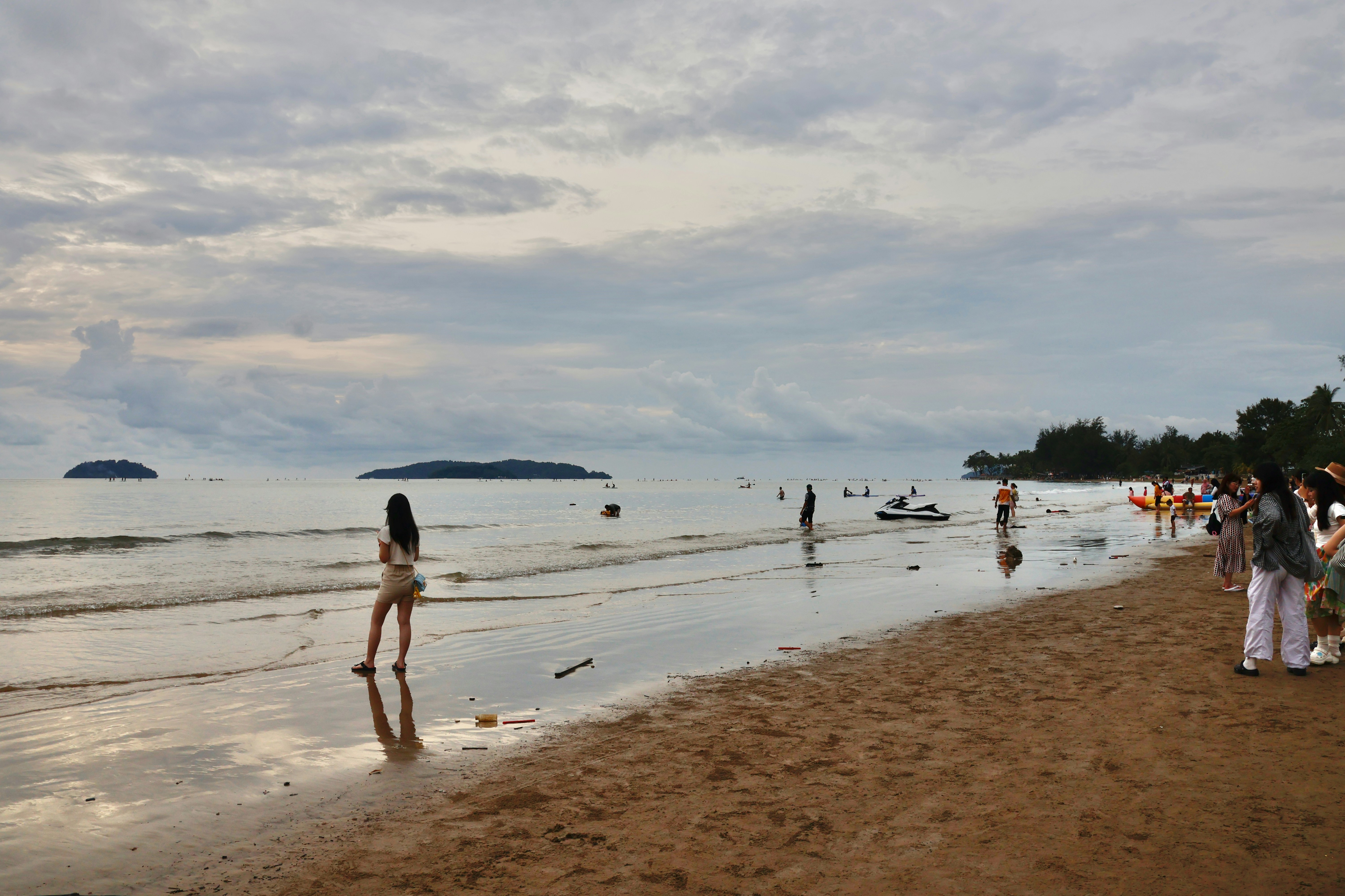 People enjoying a cloudy day at a sandy beach.