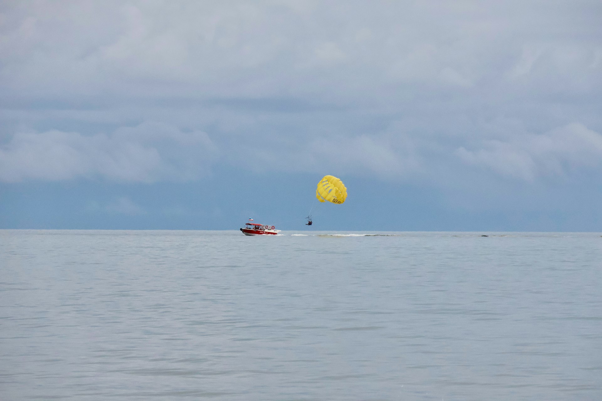 A boat pulls a person parasailing on the water.