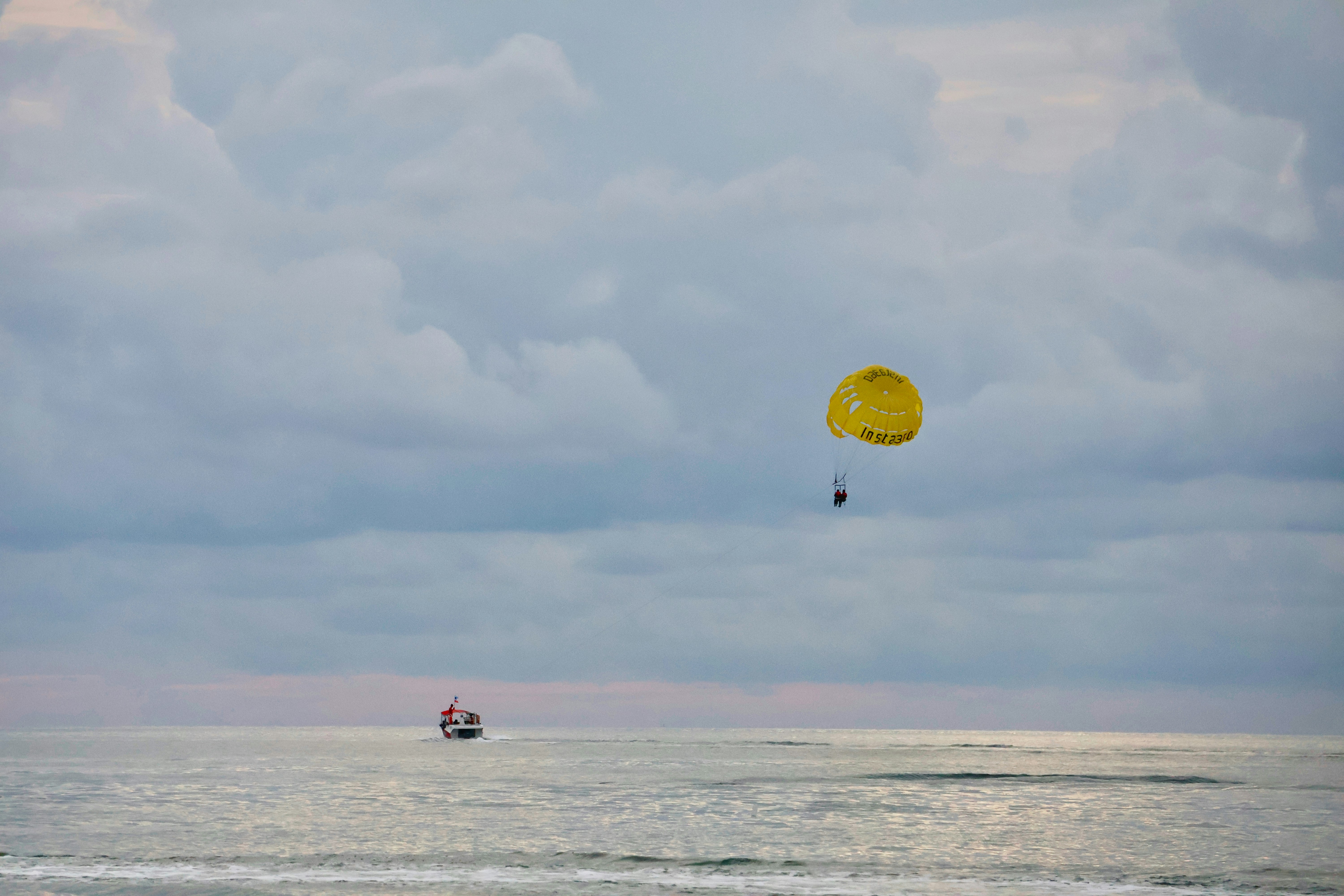 Tourist enjoying parasailing pulled by a boat over the sea